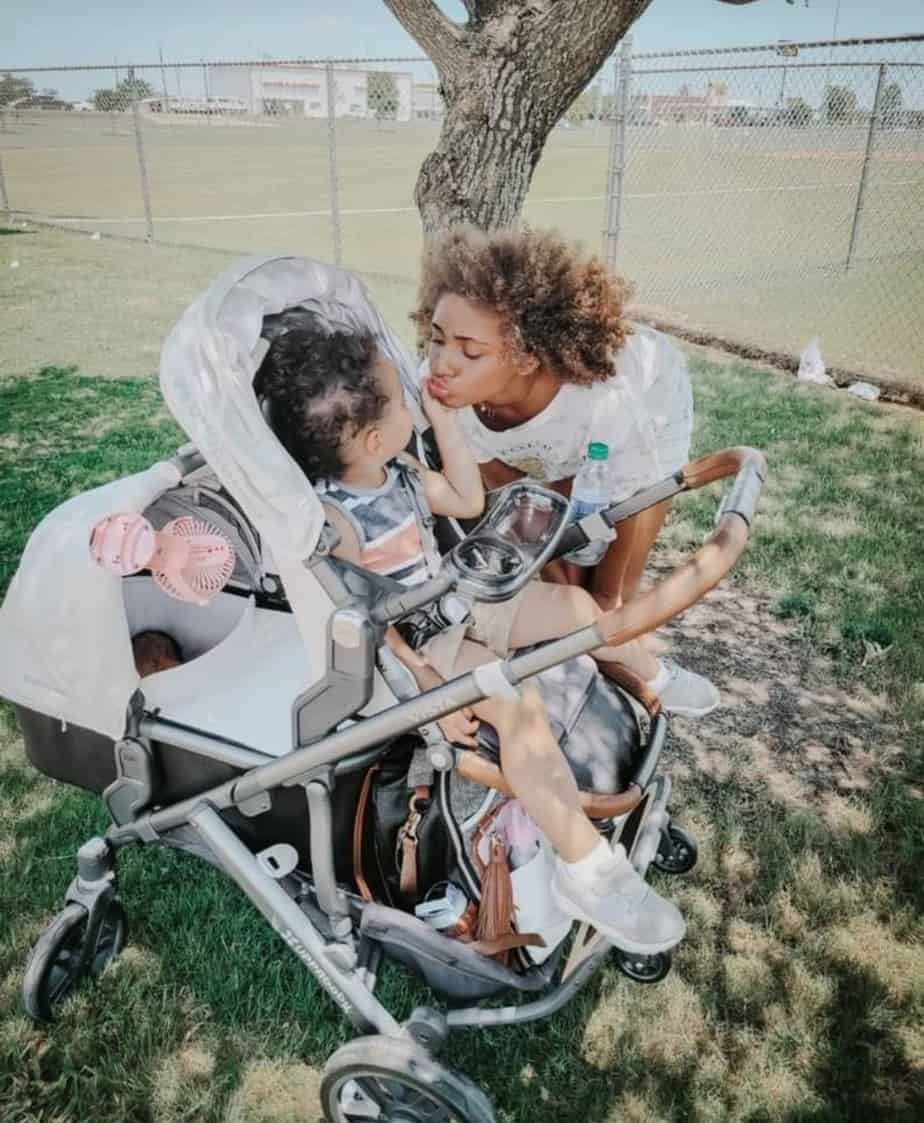 mother kissing her daughter in uppababy stroller