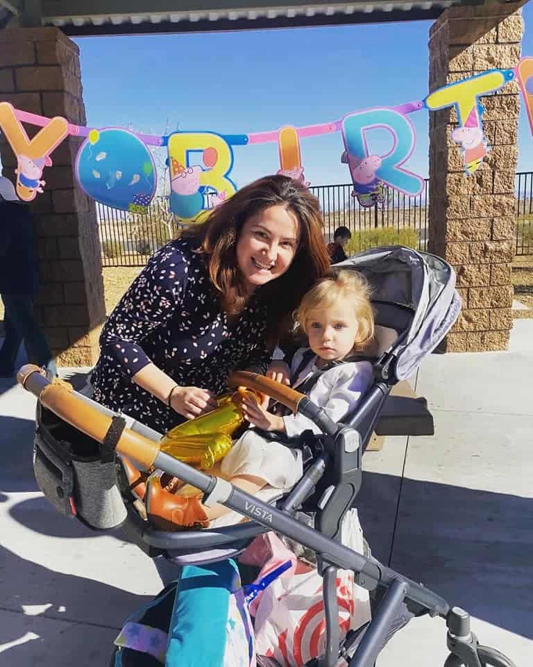 mother poses with her baby in uppababy stroller