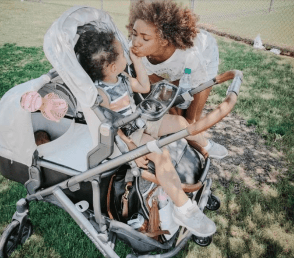 mother kissing her daughter in uppababy stroller