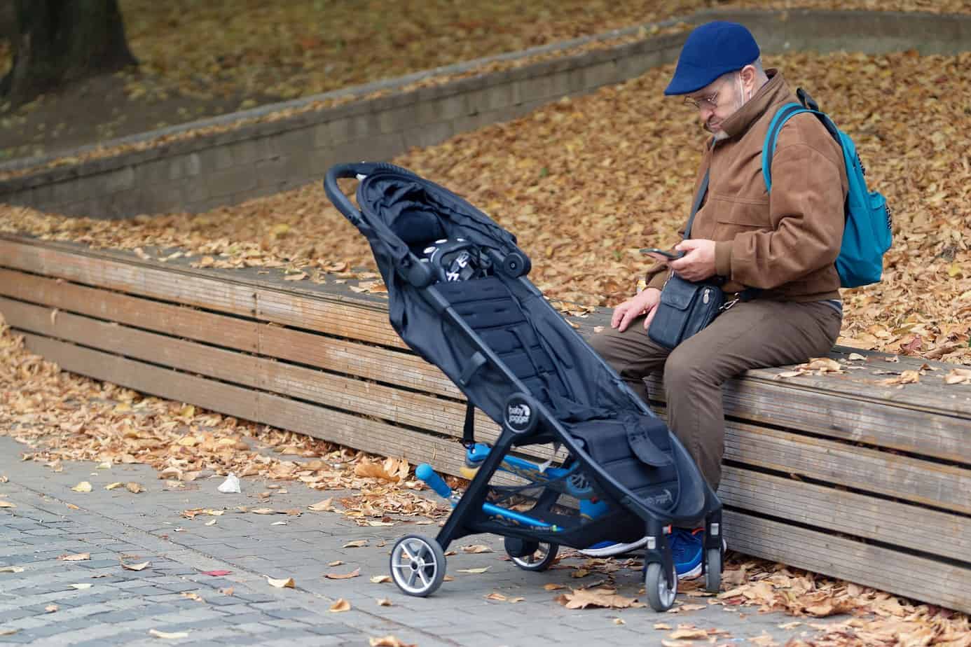 a man sitting in the park with a stroller