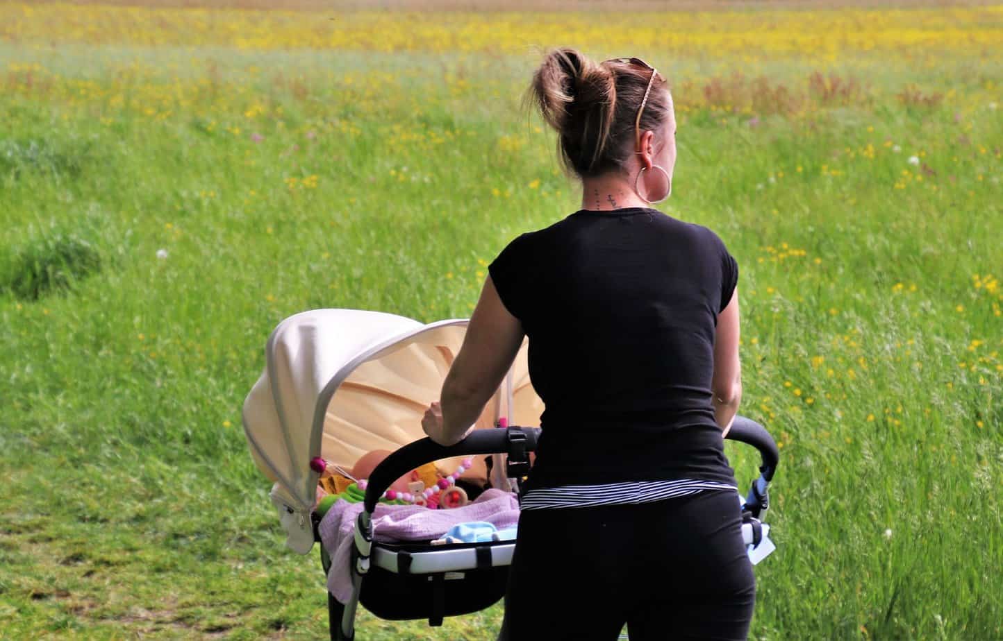 mother walking in the field with her baby in a stroller
