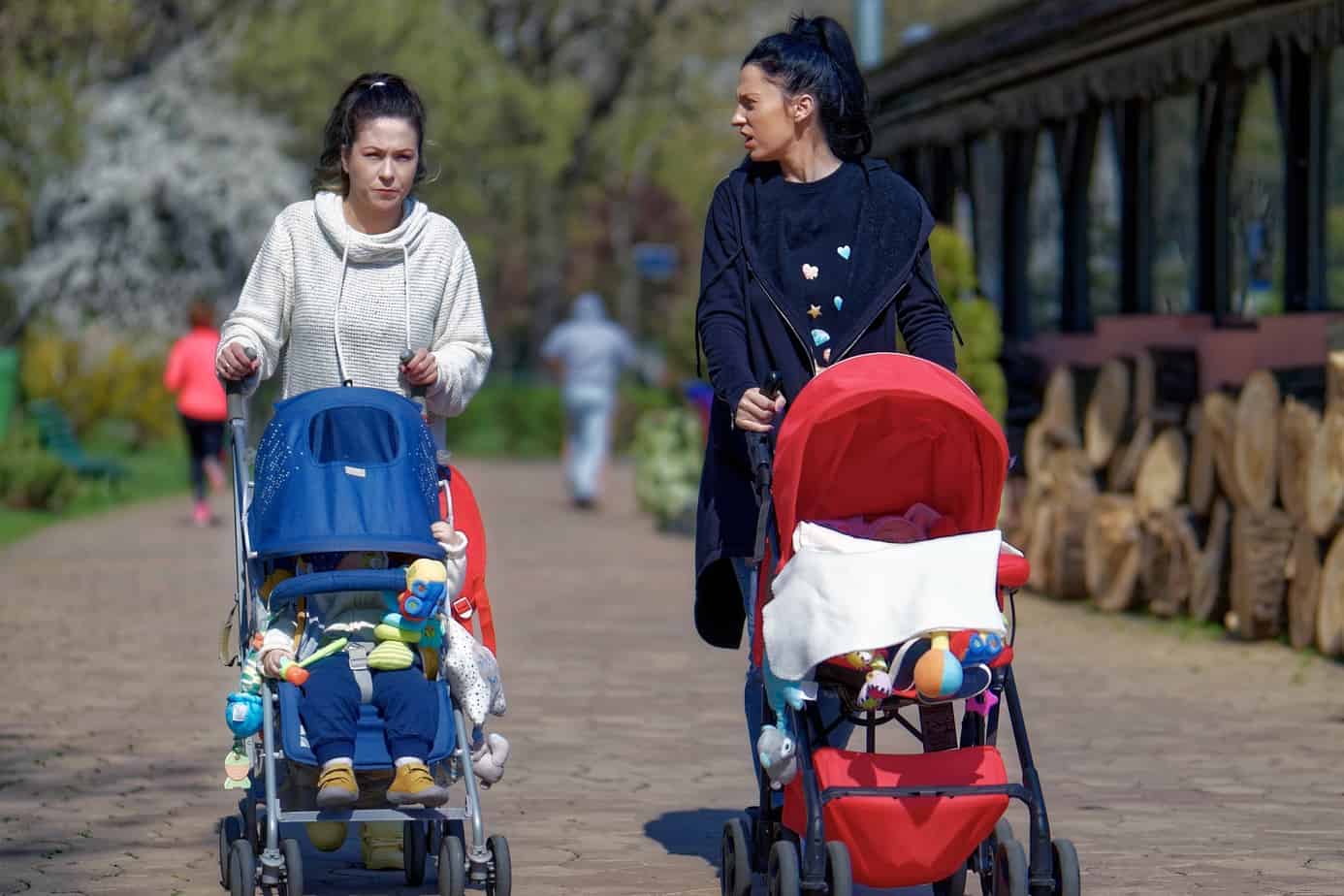 two women walking with their children in strollers