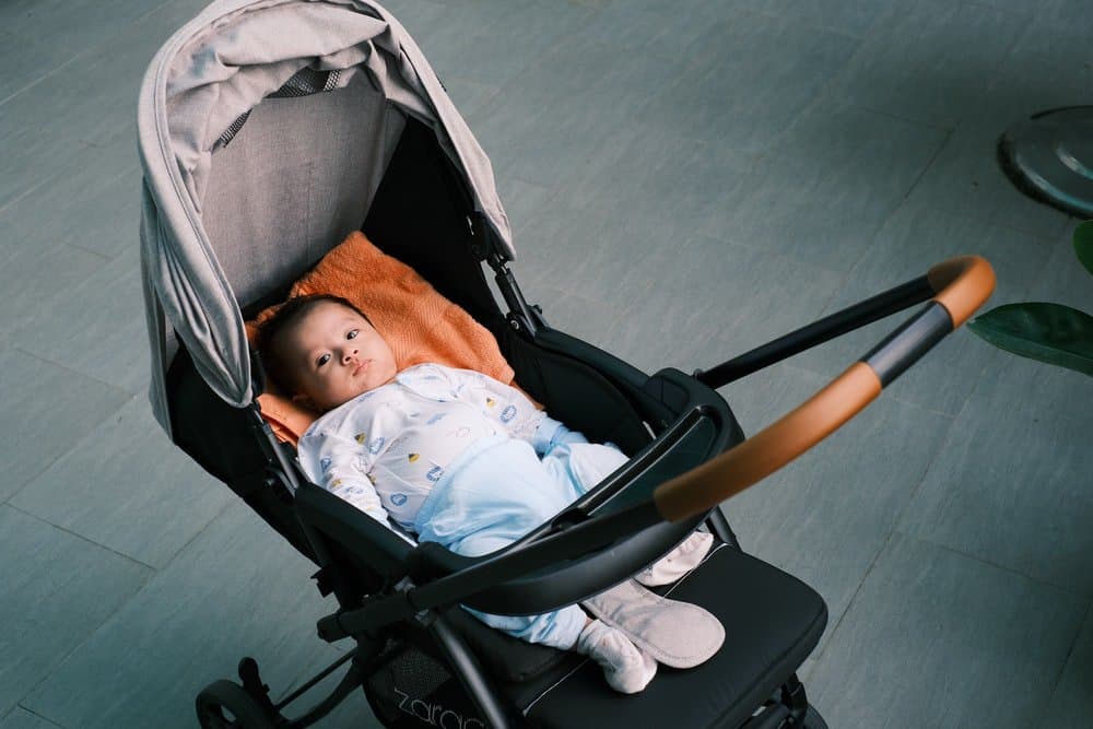 baby laying in the black and gray stroller 