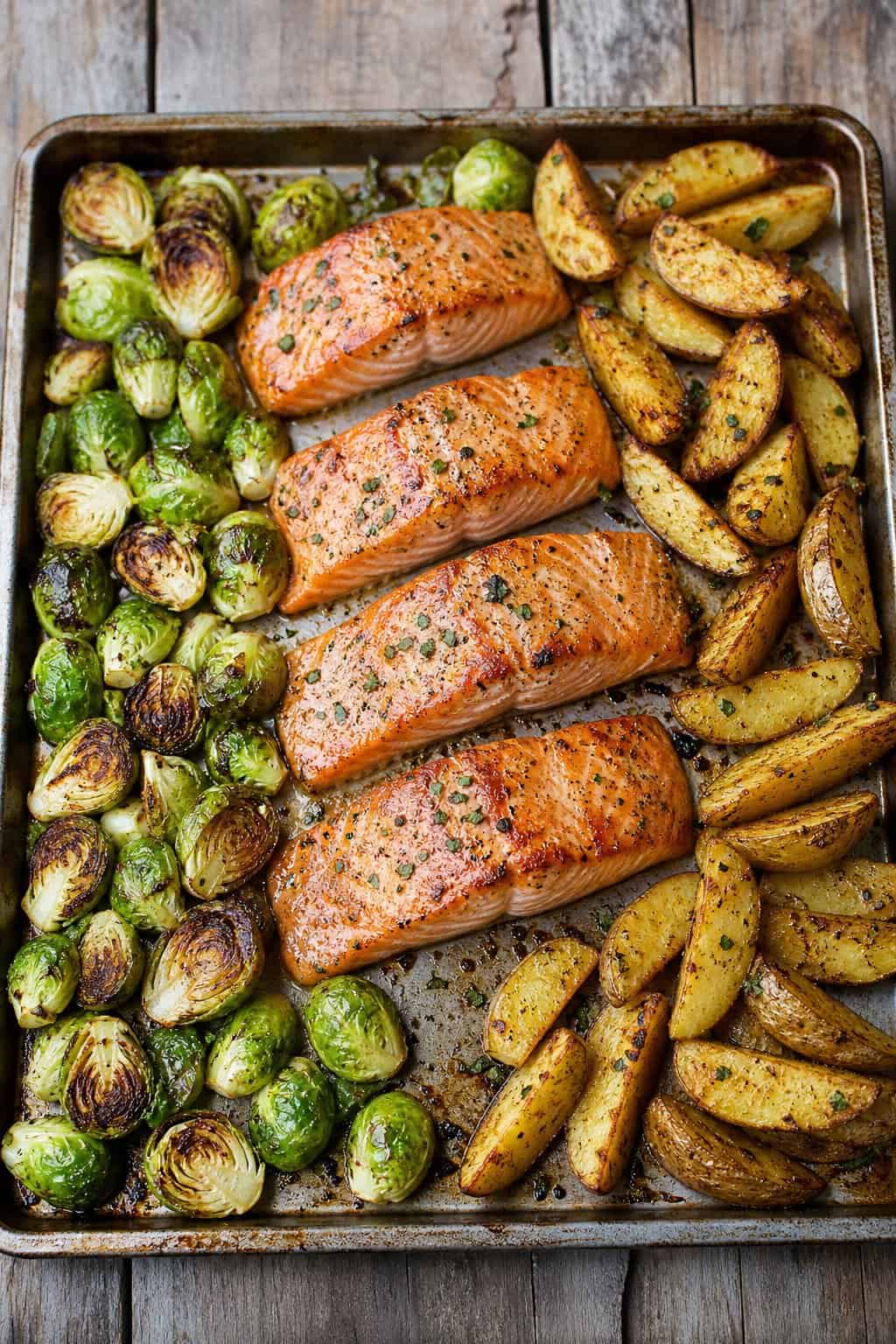 14 Easy Recipes For 2 People With Zero Waste: Delicious Meals for Two Without the Waste 3 A sheet-pan meal with roasted salmon, Brussels sprouts, and potato wedges on a wooden table.