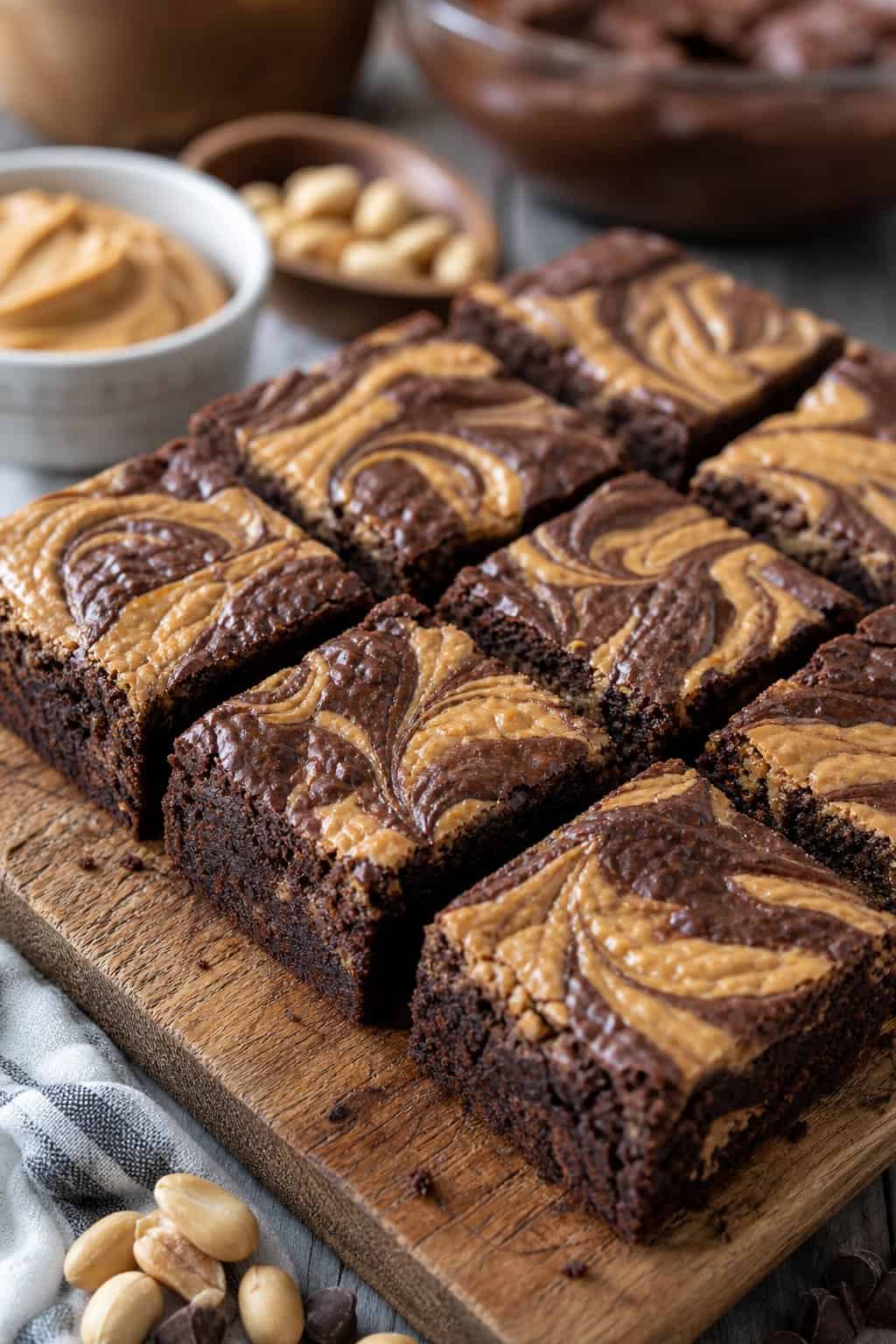 22 Recipes That Start With Brownie Mix 2 Close-up of square brownie bars with peanut butter swirls on a wooden board with baking ingredients in the background.