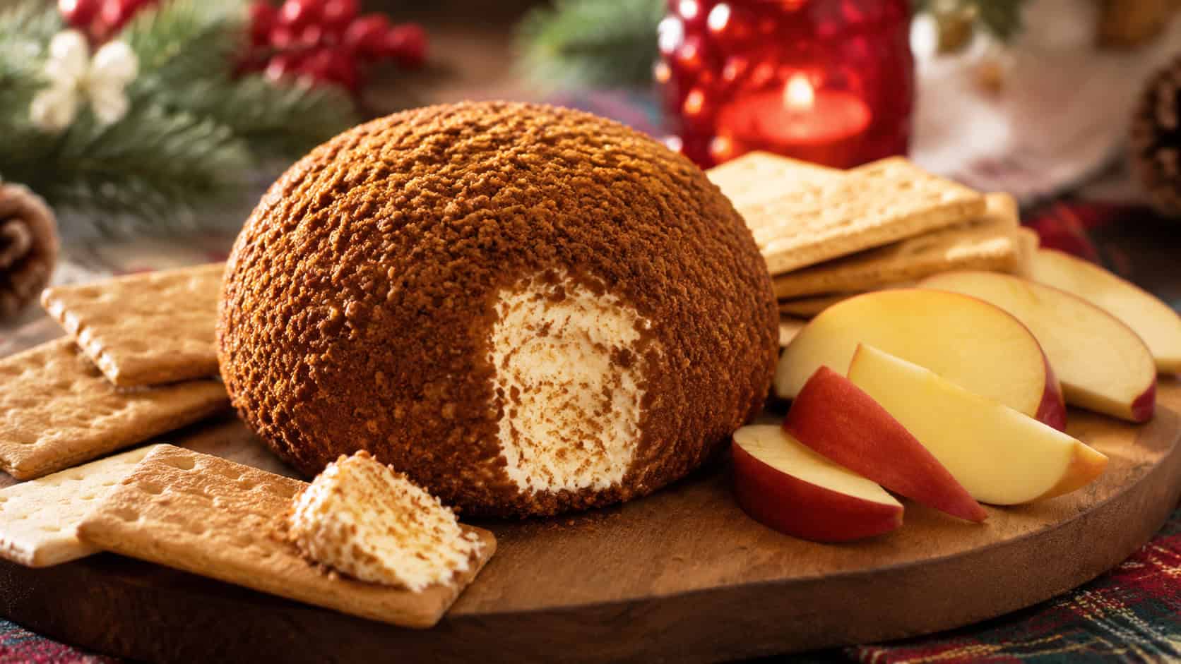 a gingersnap-crusted cheese ball on a wooden board in a wide horizontal shot, surrounded by graham crackers and apple slices, cozy holiday table, warm natural light, shallow depth of field, landscape orientation