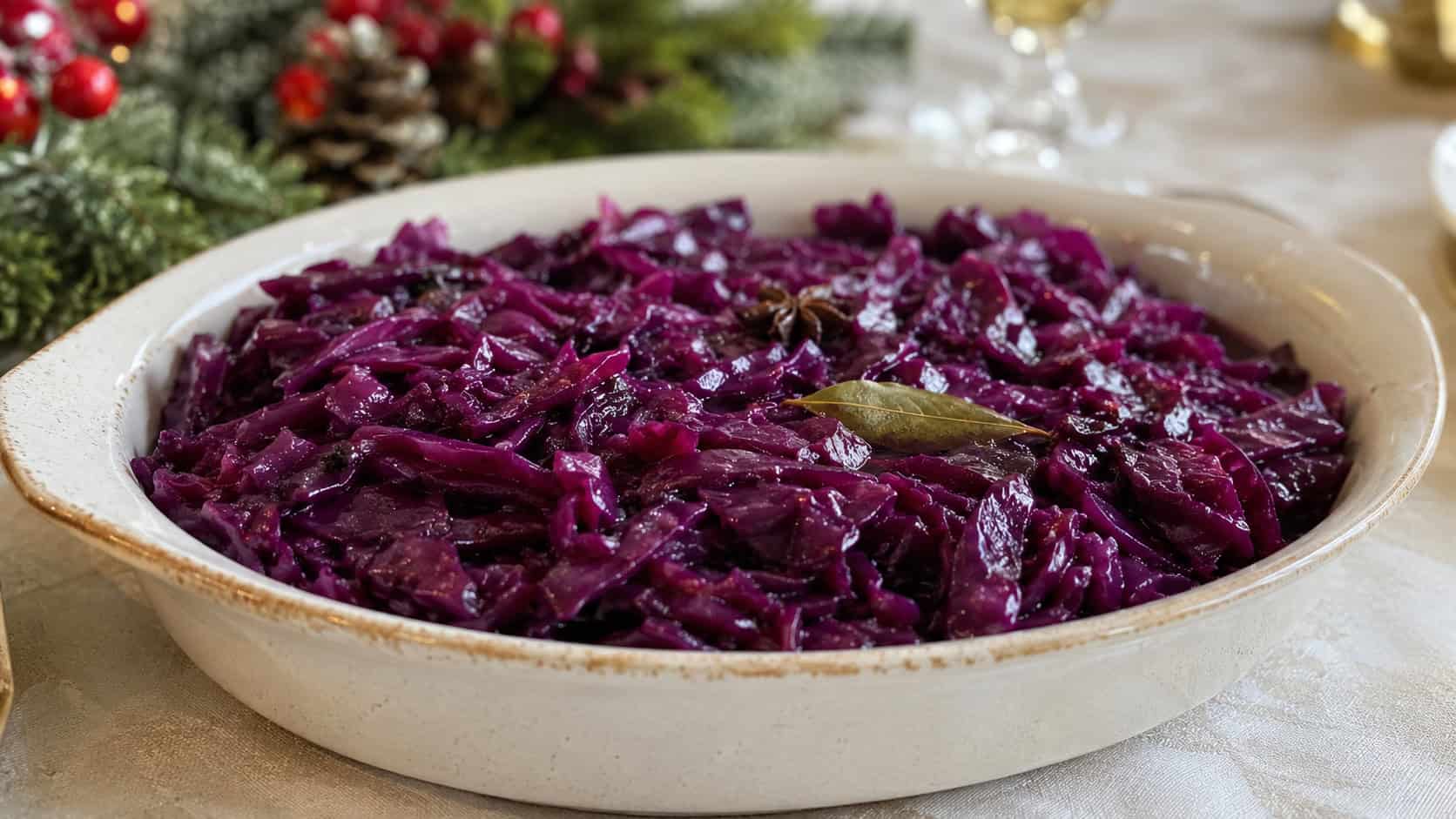 glossy spiced braised red cabbage with deep purple color in a wide horizontal shot, served in a ceramic dish on a holiday table, natural light, shallow depth of field, landscape orientation