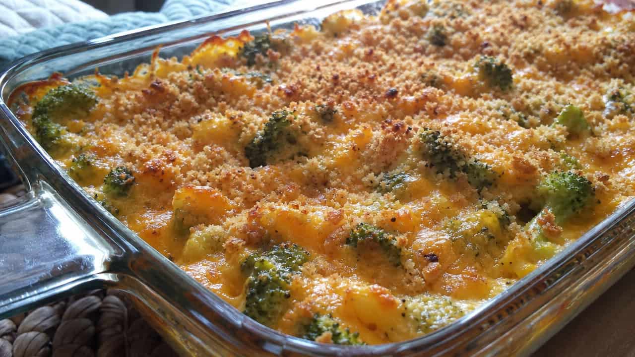 a cheesy broccoli bake with golden bubbling cheddar sauce and crisp breadcrumb topping in a wide horizontal shot, in a baking dish, natural light, shallow depth of field, landscape orientation