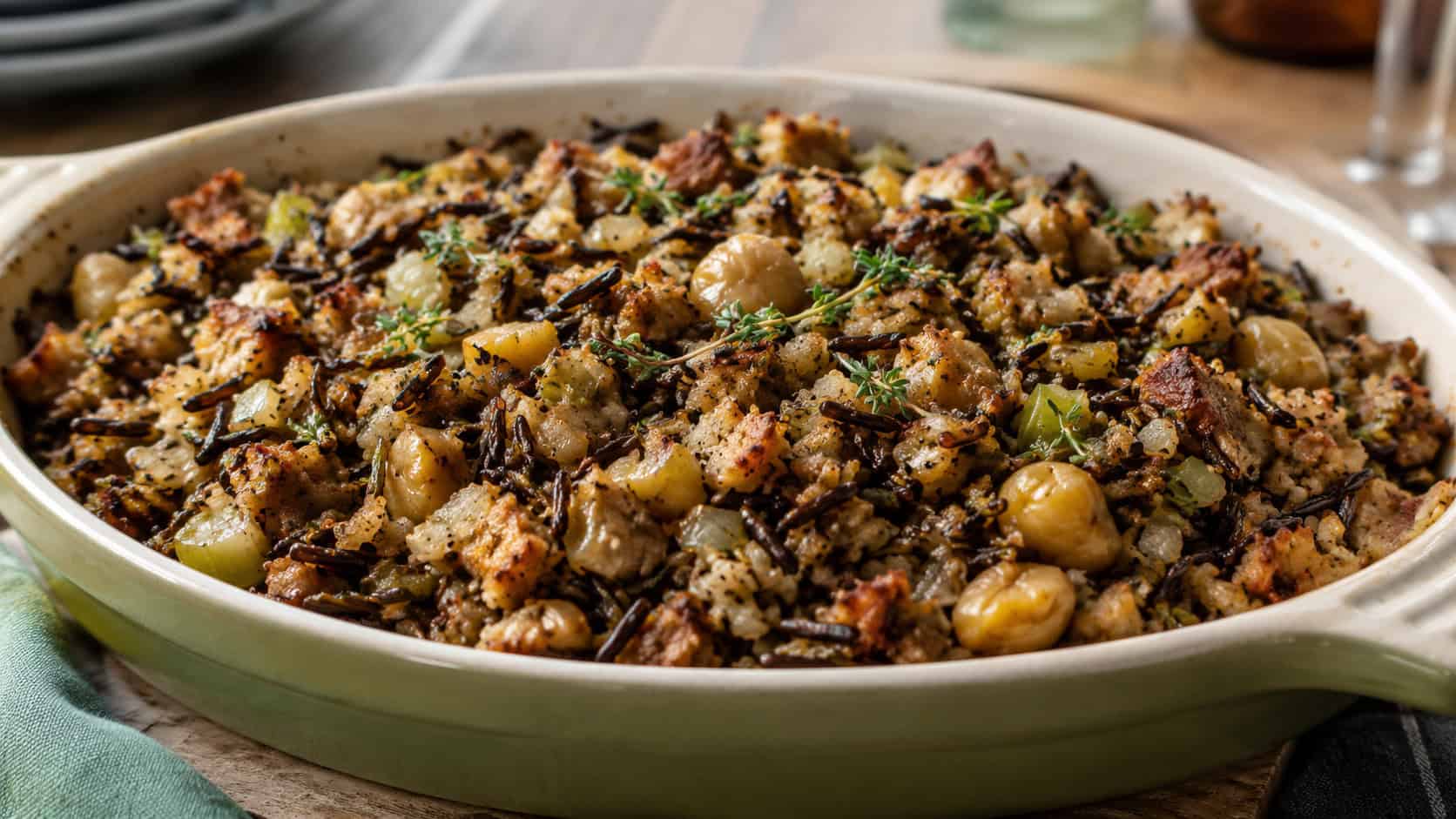 a chestnut and wild rice stuffing with dark grains, chestnuts, and herbs in a wide horizontal shot, served in a rustic baking dish, natural light, shallow depth of field, landscape orientation