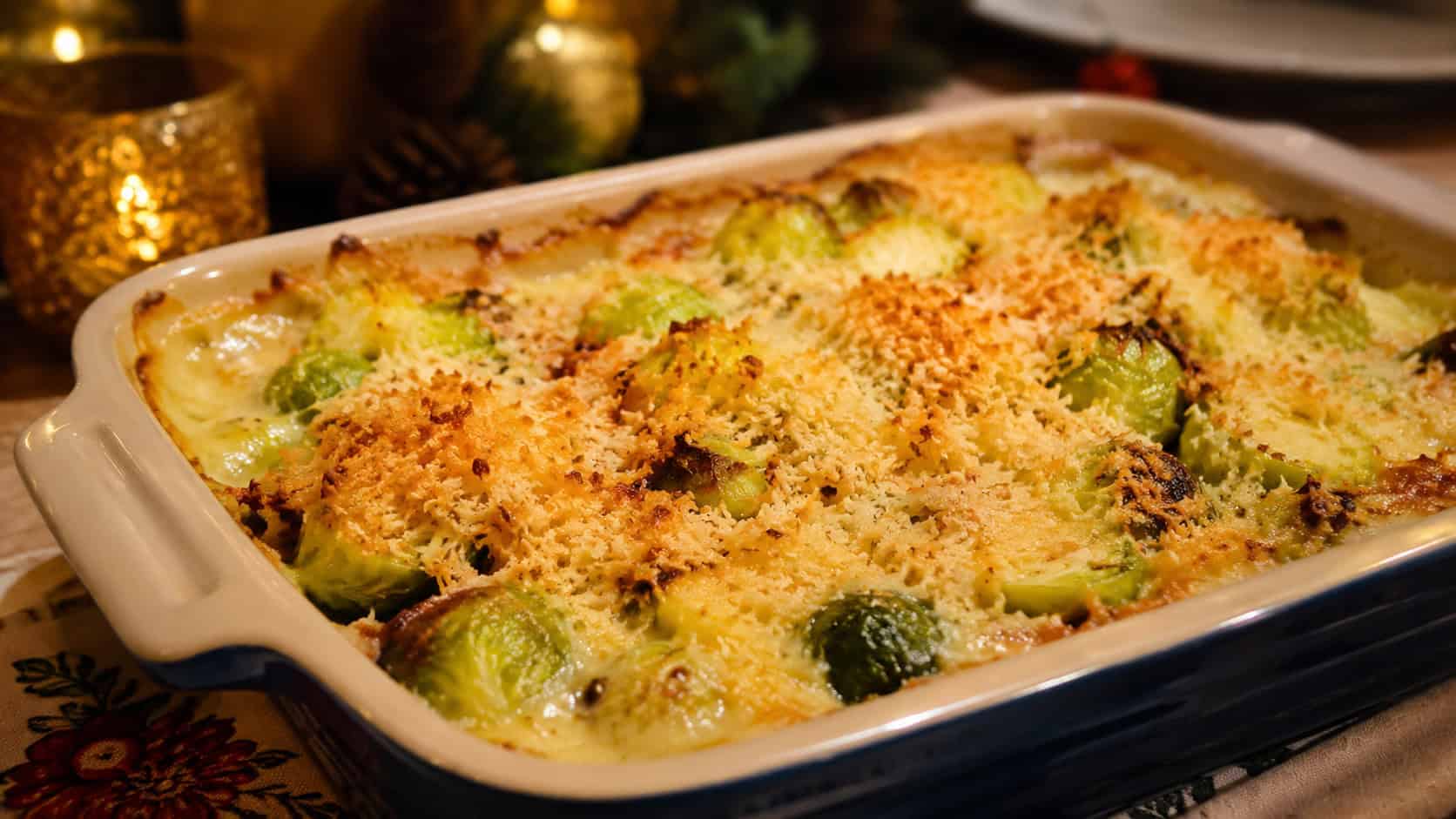 a bubbling Brussels sprout gratin with golden cheesy breadcrumb topping, in a wide horizontal shot in a ceramic baking dish on a holiday table, warm inviting light, shallow depth of field, landscape orientation