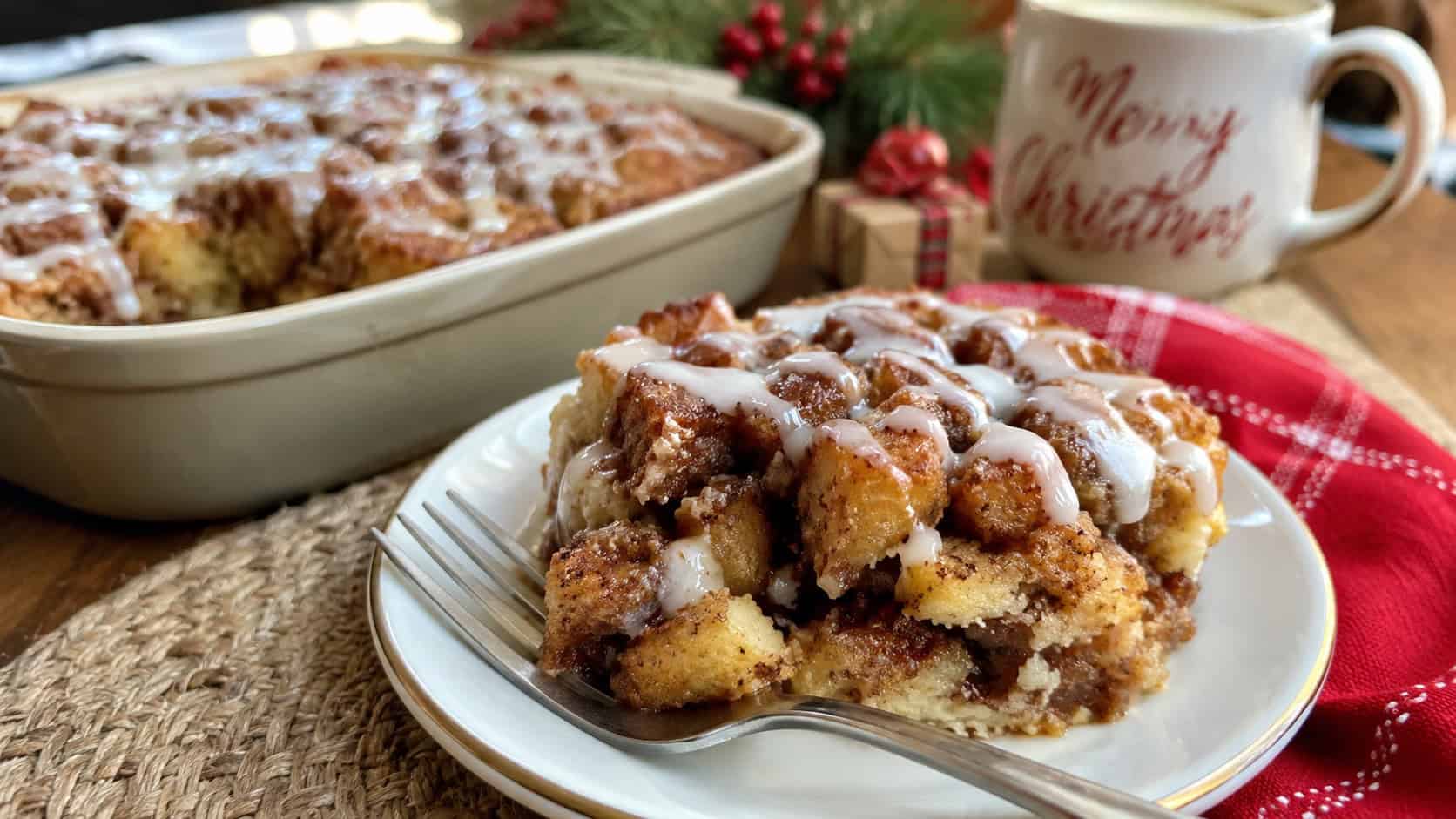 gooey cinnamon roll French toast casserole with white icing drizzled over golden pieces in a wide horizontal shot, scooped onto a plate with a fork, cozy Christmas-morning table, natural light, shallow depth of field, landscape orientation
