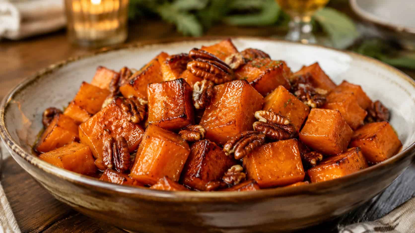 glossy maple pecan sweet potatoes in a rustic serving bowl in a wide horizontal shot, caramelized edges and toasted nuts, warm holiday table, natural light, shallow depth of field, landscape orientation