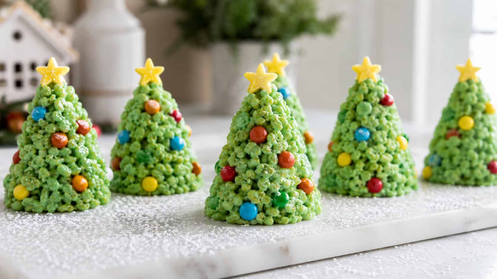 a row of green rice cereal Christmas trees decorated with colorful candy ornaments and star toppers, in a wide horizontal shot on a white marble board with a dusting of powdered sugar like snow, bright natural light, shallow depth of field, landscape orientation