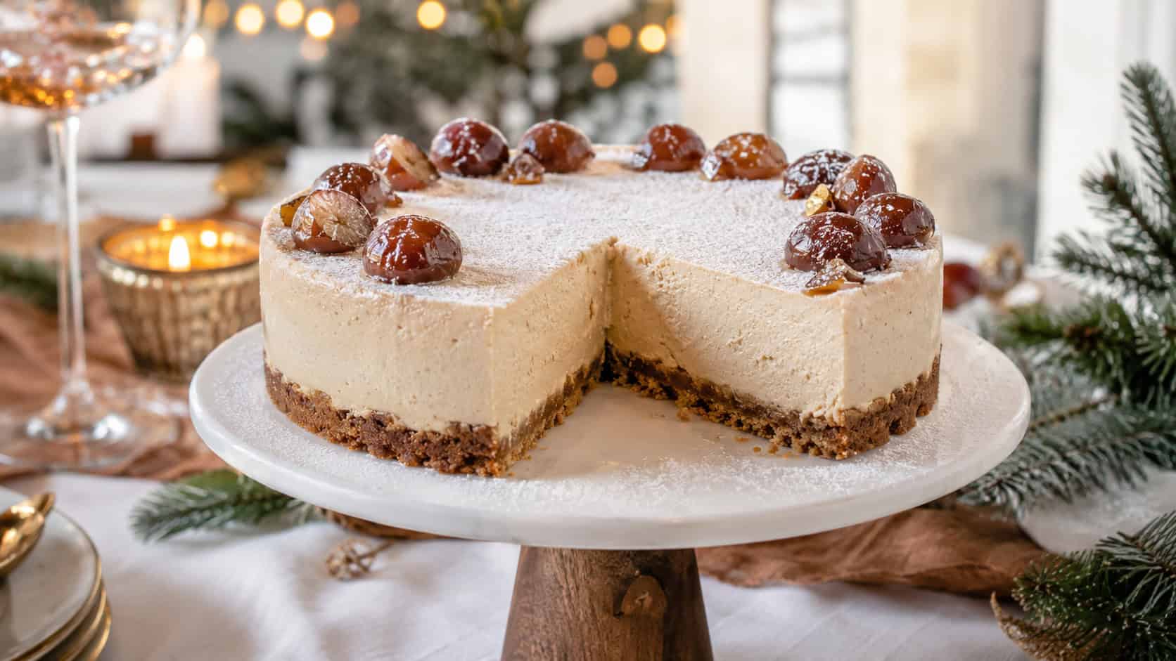 a chestnut cheesecake on a cake stand in a wide horizontal shot, dusting of powdered sugar over a smooth creamy top with candied chestnuts, one slice removed, on an elegant holiday table, warm natural light, shallow depth of field, landscape orientation