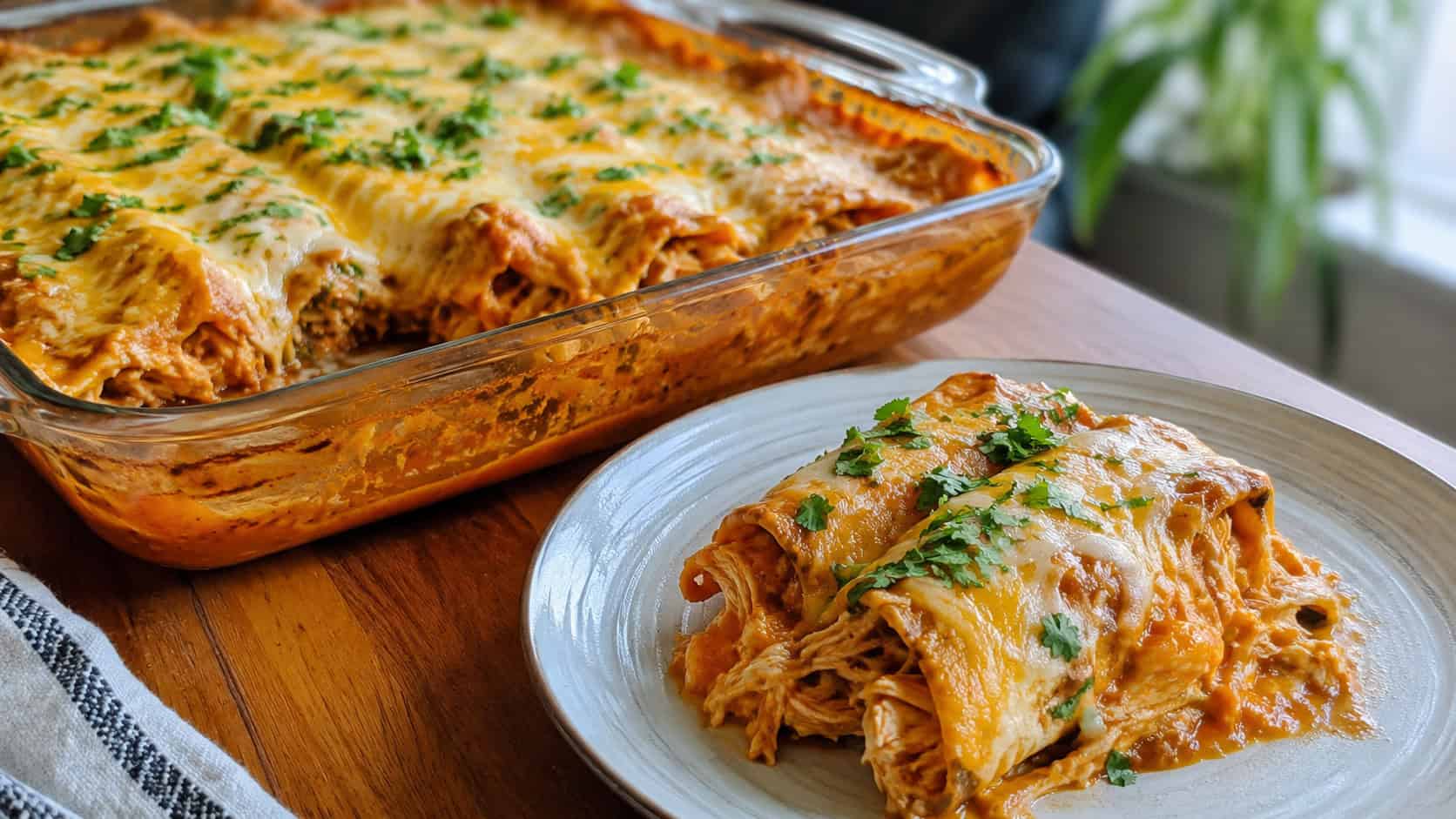 saucy cheese-topped chicken enchiladas in a baking dish with one scooped onto a plate, wide horizontal shot, melted cheese and cilantro garnish, warm natural light, shallow depth of field, landscape orientation