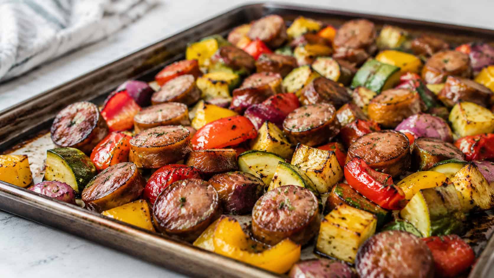 sheet pan sausage and veggies in a wide horizontal shot, colorful roasted peppers, zucchini, and sausage on a baking sheet, natural light, shallow depth of field, landscape orientation