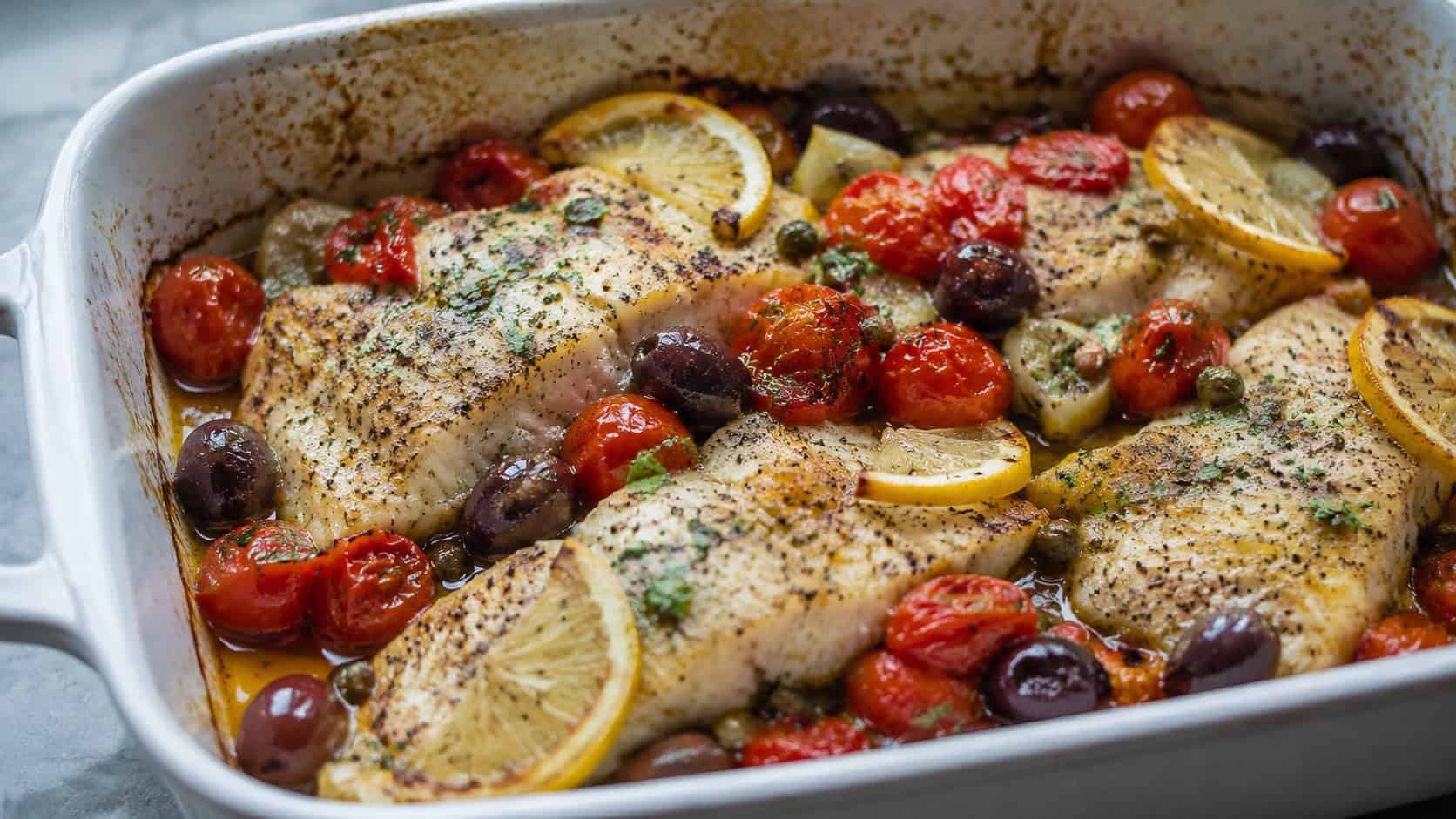 Mediterranean baked cod in a wide horizontal shot, flaky white fish with burst cherry tomatoes, olives, and lemon in a baking dish, natural light, shallow depth of field, landscape orientation