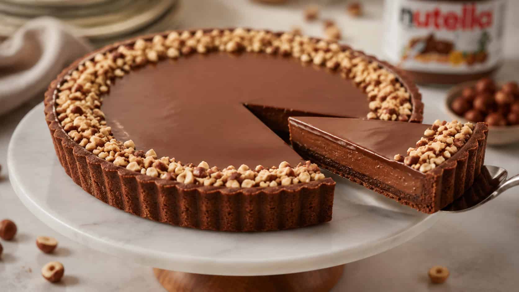 a Nutella tart on a cake stand in a wide horizontal shot, glossy smooth chocolate surface, edge ringed with chopped hazelnuts, one slice lifted out, elegant soft light, shallow depth of field, landscape orientation