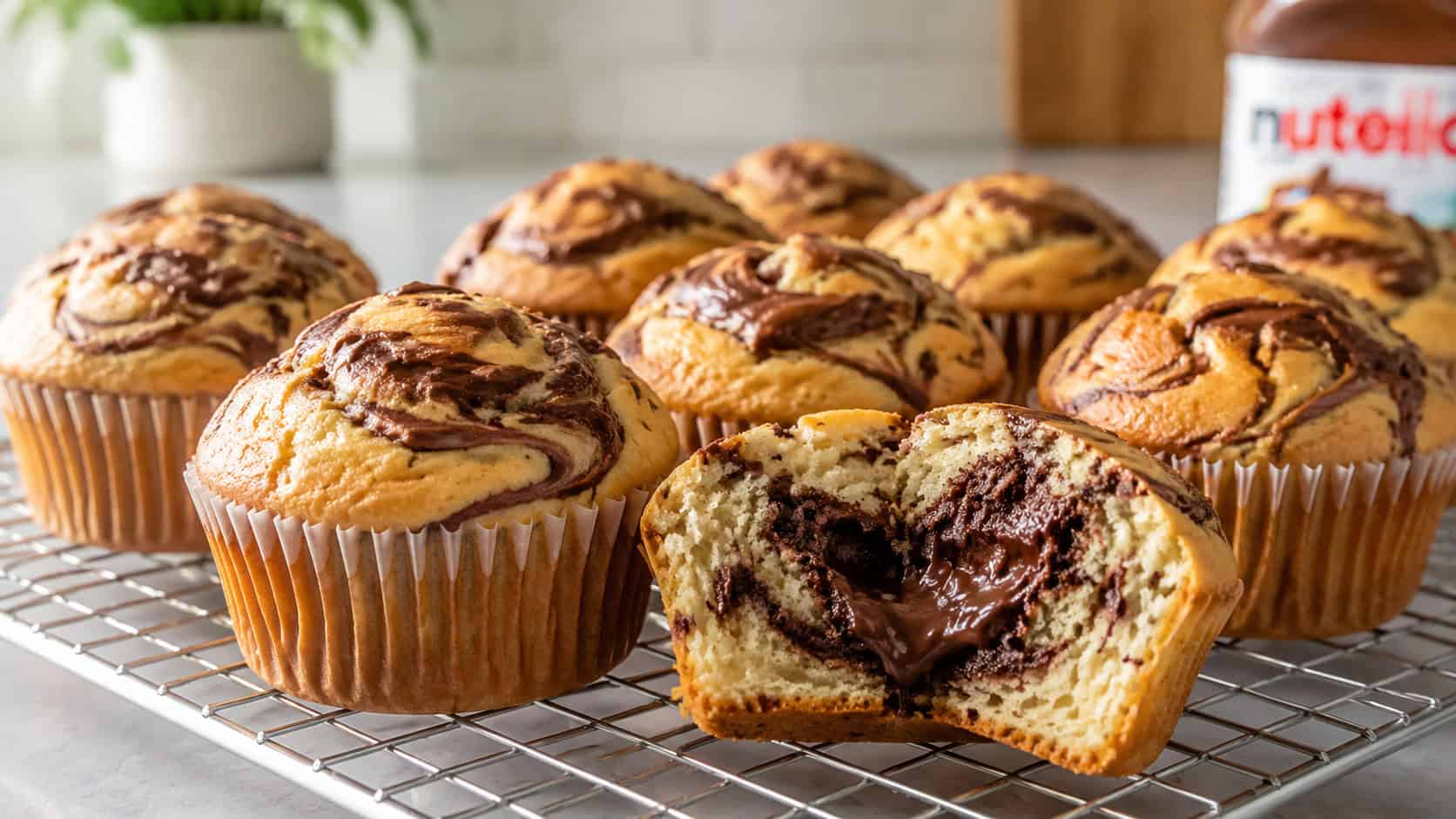 Nutella swirl muffins on a cooling rack in a wide horizontal shot, golden domed tops with dark chocolate swirls, one split open showing the gooey center, bright kitchen light, shallow depth of field, landscape orientation
