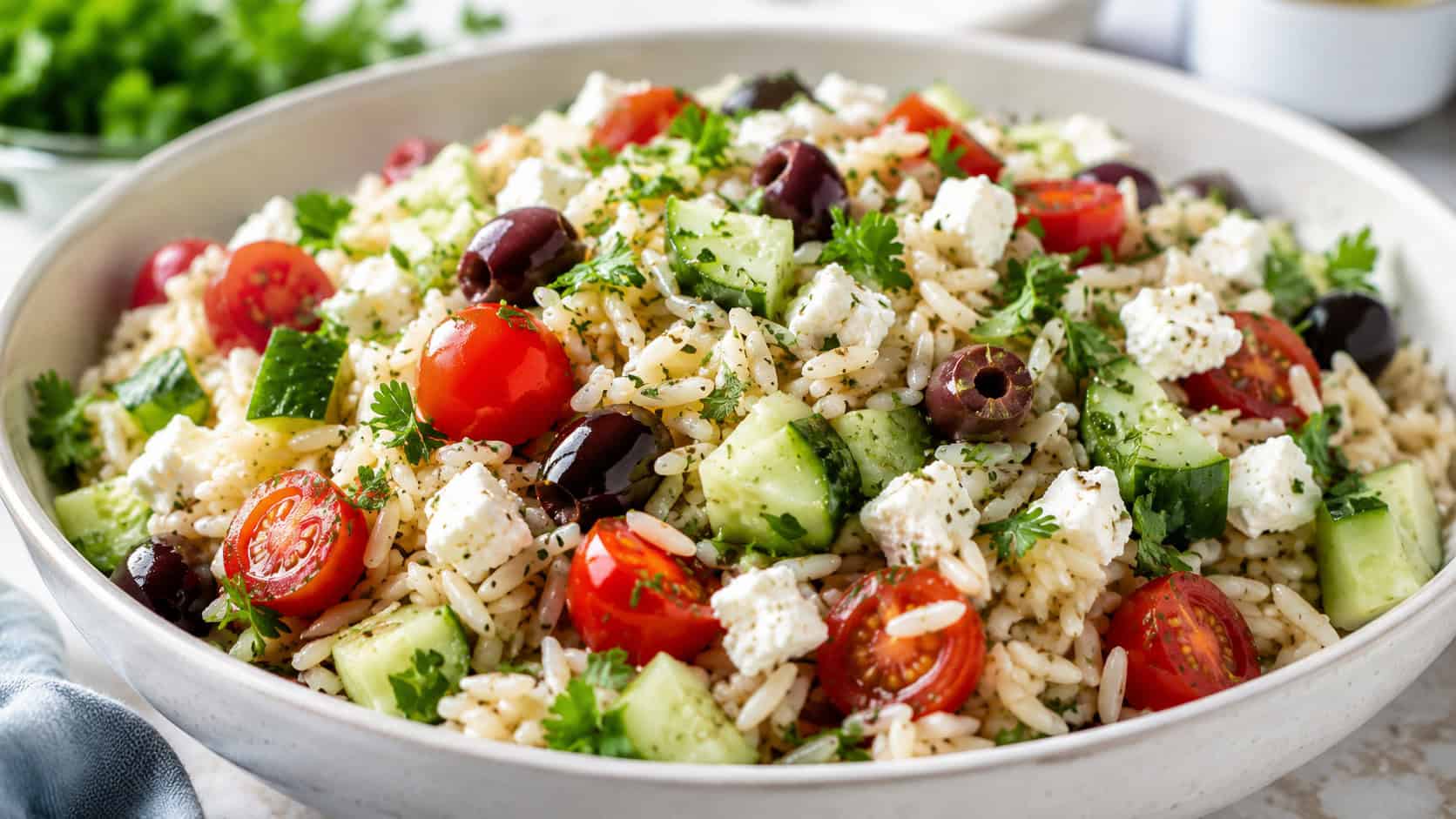 a fresh Mediterranean rice salad with cucumber, cherry tomatoes, feta, and olives in a wide horizontal shot in a serving bowl, sprinkled with parsley, bright natural light, shallow depth of field, landscape orientation