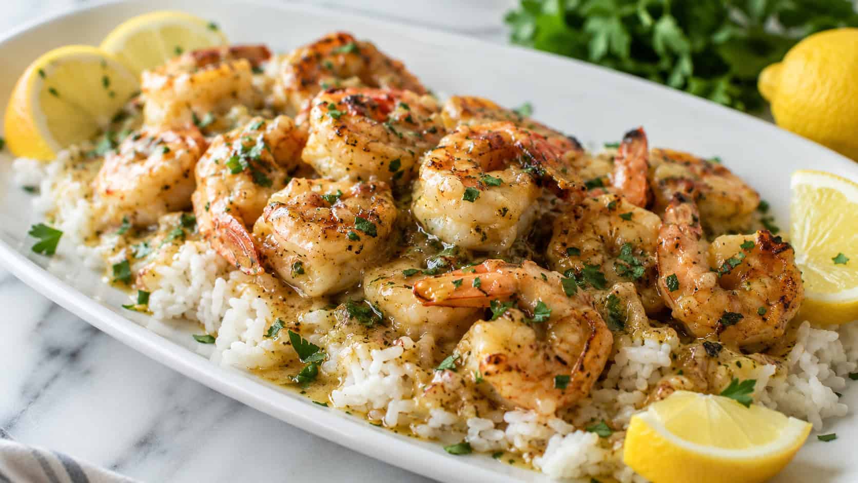 a wide horizontal plate of garlic butter shrimp over white rice with lemon wedges and parsley, glistening sauce, on a light marble surface, bright natural light, shallow depth of field, landscape orientation
