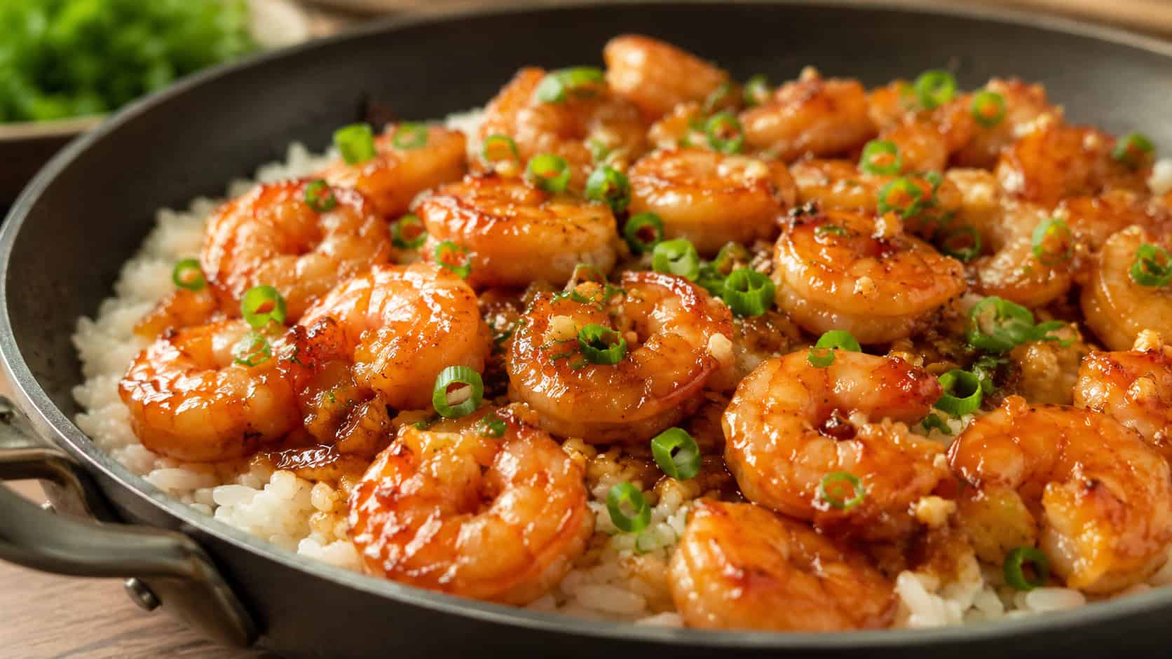 honey garlic shrimp in a wide horizontal shot, glossy glazed shrimp in a skillet with a sprinkle of scallions over rice, warm natural light, shallow depth of field, landscape orientation