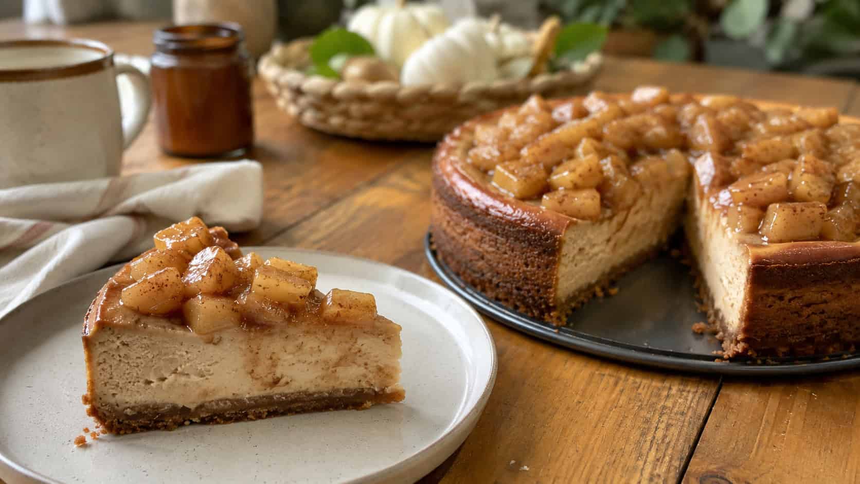 a cinnamon cheesecake topped with glistening spiced apple chunks, one slice served on a plate, in a wide horizontal shot on a cozy wooden table, natural light, shallow depth of field, landscape orientation