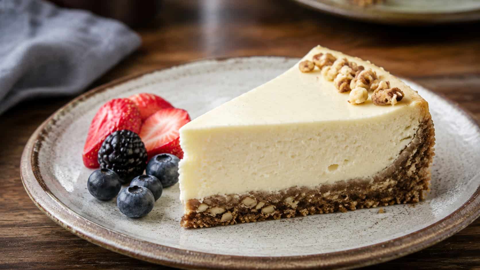 a creamy gluten-free vanilla cheesecake slice with a golden nutty crust on a rustic plate, fresh berries on the side, on a wooden table, wide horizontal shot, natural light, shallow depth of field, landscape orientation