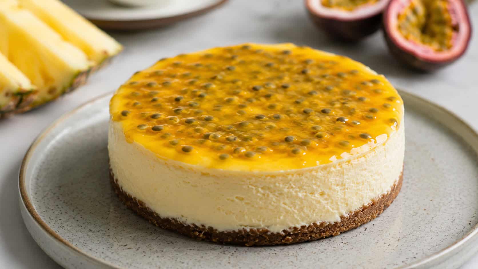 a gluten-free pineapple cheesecake topped with golden passion fruit pulp in a wide horizontal shot, on a ceramic plate, bright natural light, shallow depth of field, landscape orientation