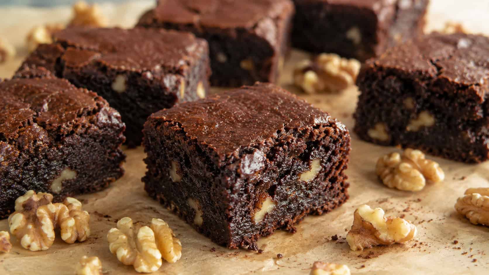 fudgy banana walnut brownies cut into squares on parchment with walnut halves scattered around, wide horizontal shot, moist interior visible, warm natural light, shallow depth of field, landscape orientation