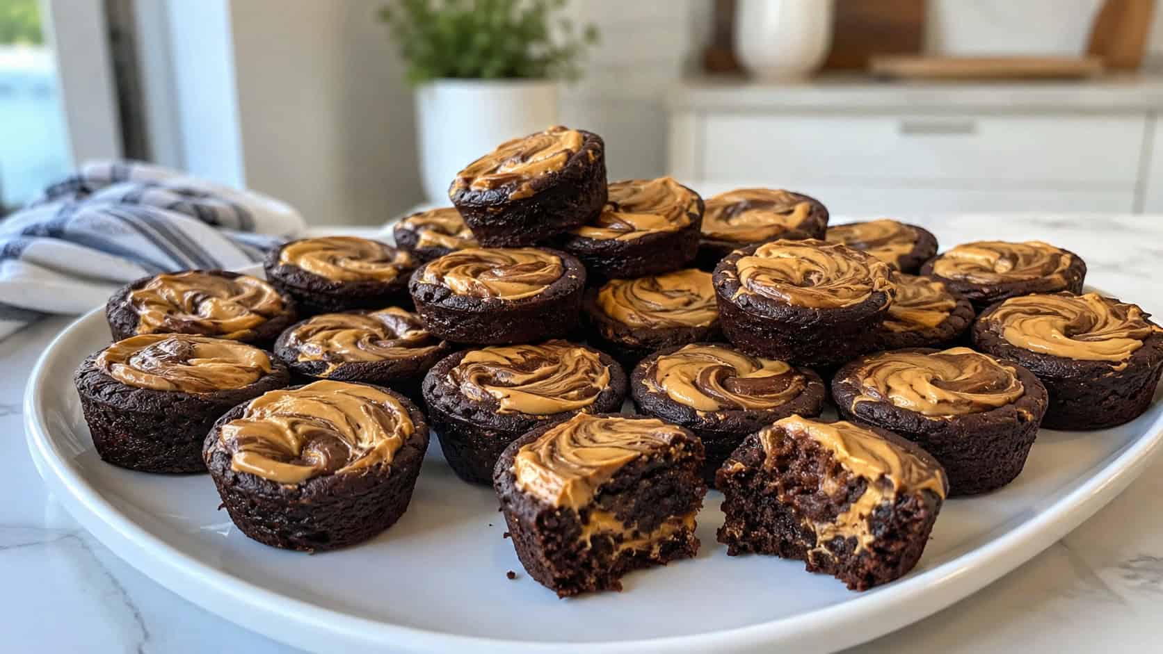 two dozen peanut butter swirl brownie bites arranged on a wide platter in a horizontal shot, each topped with a marbled peanut butter swirl, a few stacked and a couple bitten on a bright kitchen table, airy natural light, shallow depth of field, landscape orientation