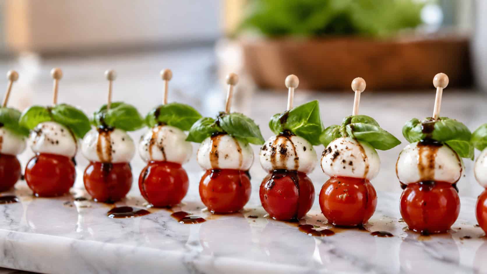 mini caprese skewers with red cherry tomatoes, white mozzarella, and green basil drizzled with balsamic, arranged in a wide horizontal line on a marble board, bright natural light, shallow depth of field, landscape orientation