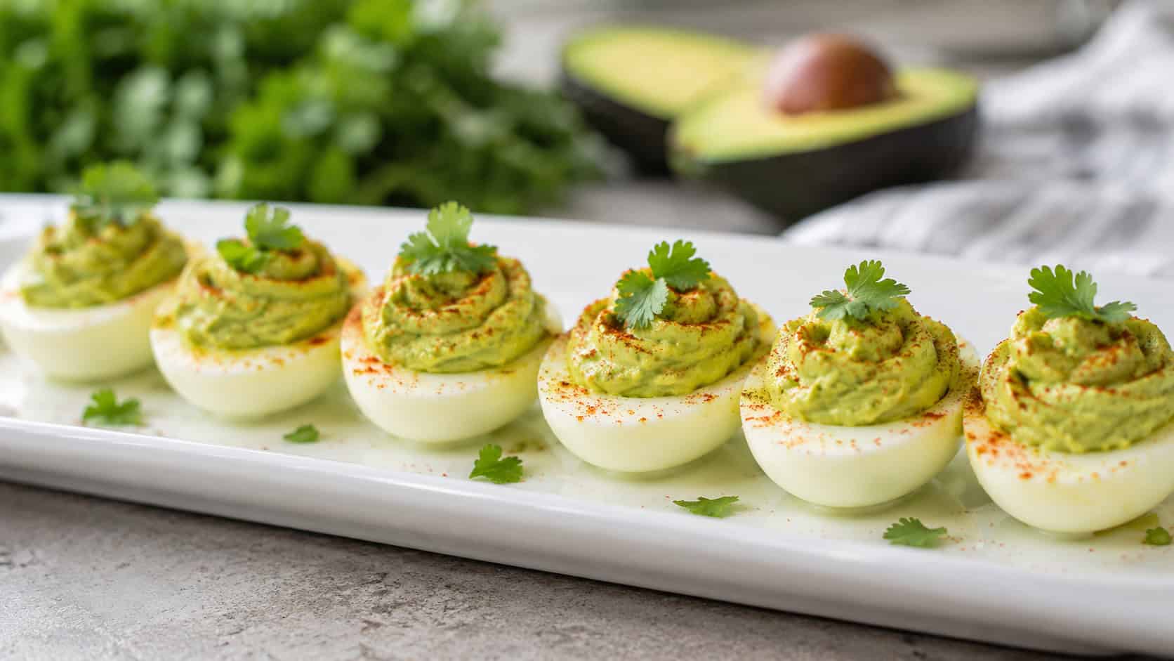 avocado deviled eggs with creamy green filling dusted with paprika and cilantro, arranged in a wide horizontal row on a white platter, fresh and vibrant, soft natural light, shallow depth of field, landscape orientation
