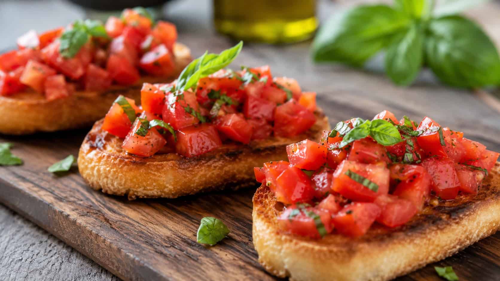 bright tomato bruschetta in a wide horizontal shot, toasts heaped with diced tomatoes and basil on a rustic wooden board, natural light, shallow depth of field, landscape orientation