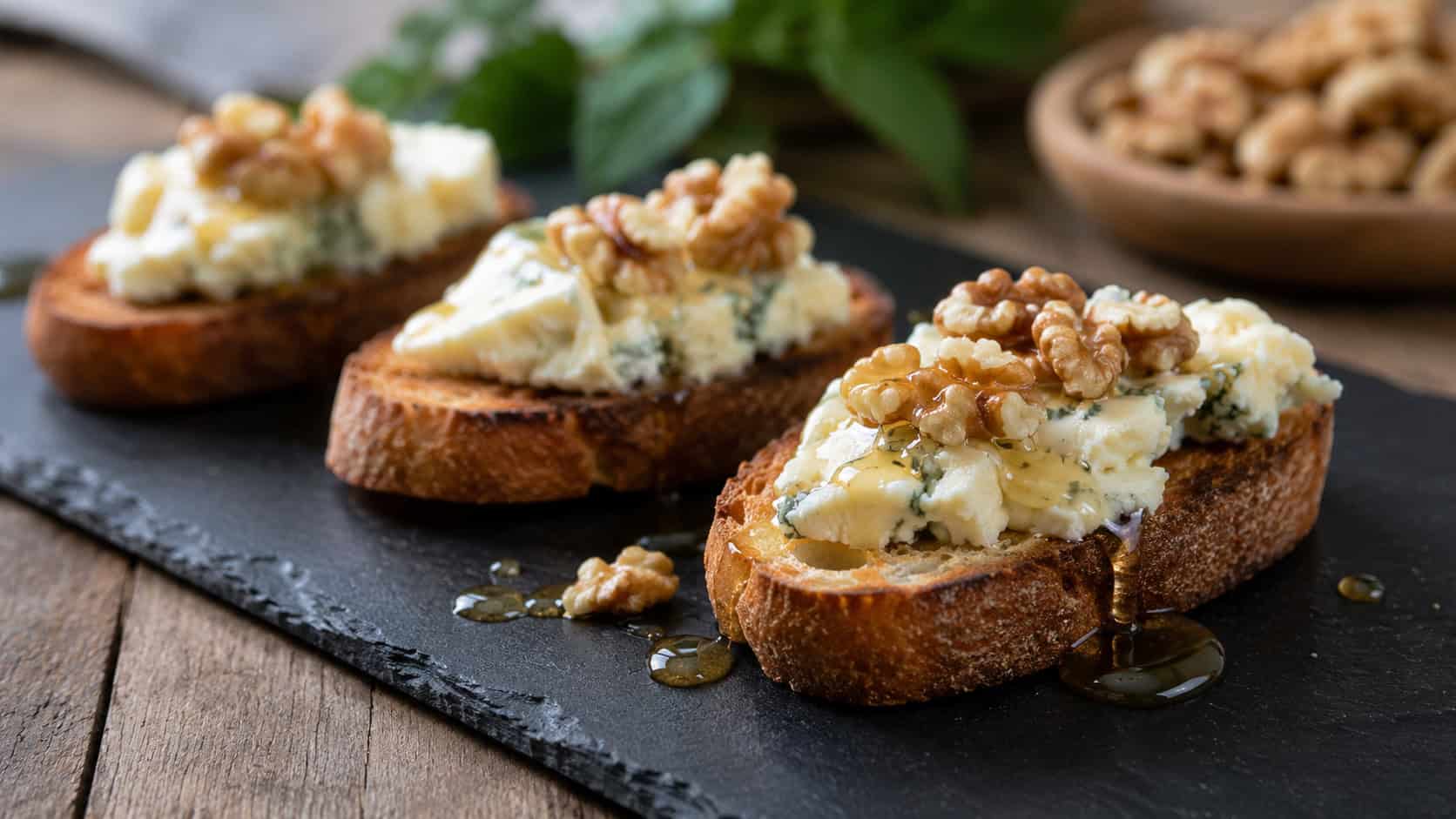 gorgonzola crostini in a wide horizontal shot, drizzled with honey and topped with walnuts on a slate board, natural light, shallow depth of field, landscape orientation
