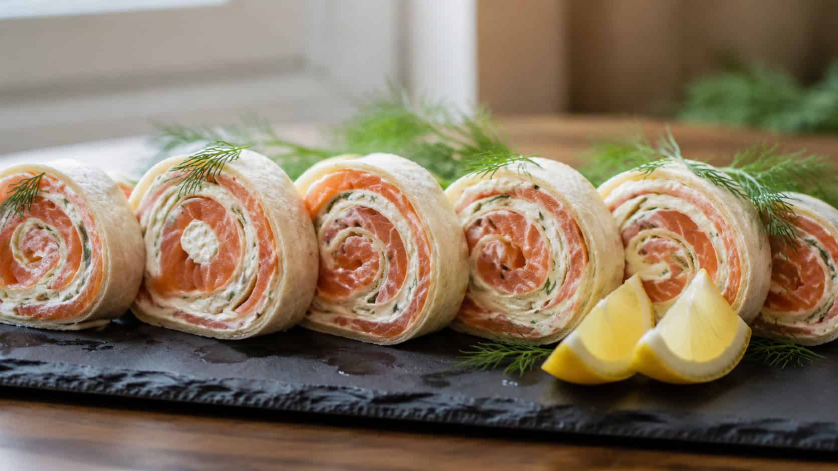 smoked salmon pinwheels arranged in a wide horizontal row on a slate serving board, garnished with fresh dill and lemon wedges, soft natural window light, shallow depth of field, landscape orientation