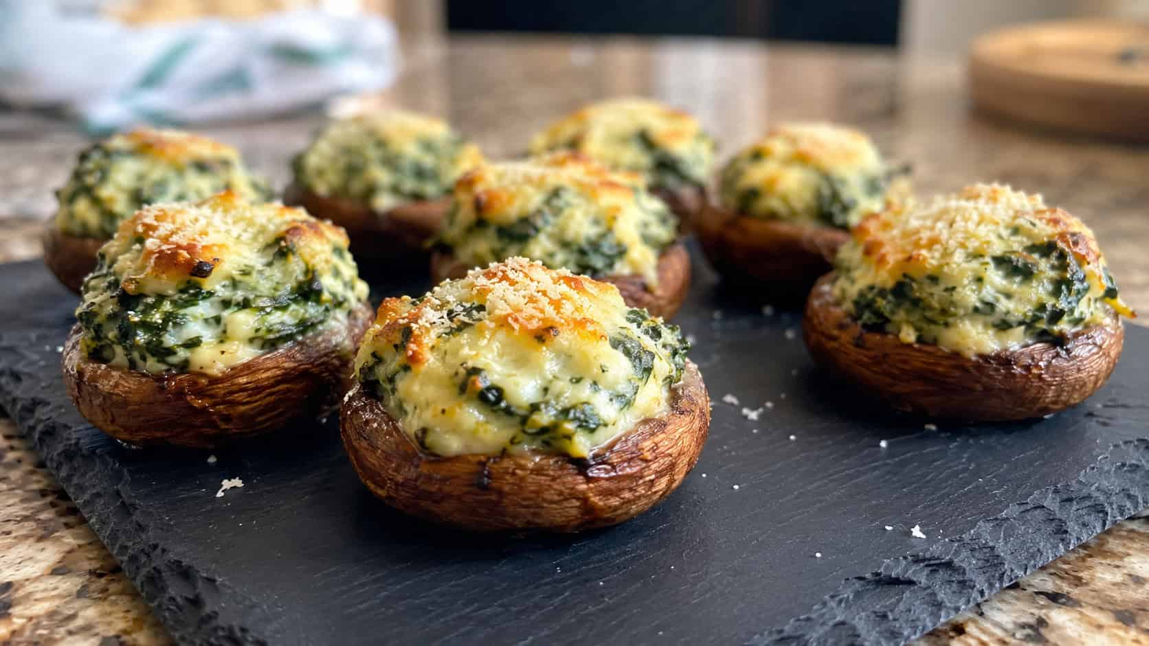 baked stuffed mushrooms filled with creamy spinach and ricotta on a slate platter, wide horizontal shot, golden tops and parmesan, warm natural light, shallow depth of field, landscape orientation