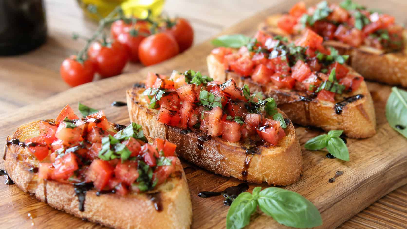 bruschetta toasts topped with diced tomatoes and basil arranged on a wooden board, wide horizontal shot, crispy golden bread, balsamic drizzle, bright natural light, shallow depth of field, landscape orientation