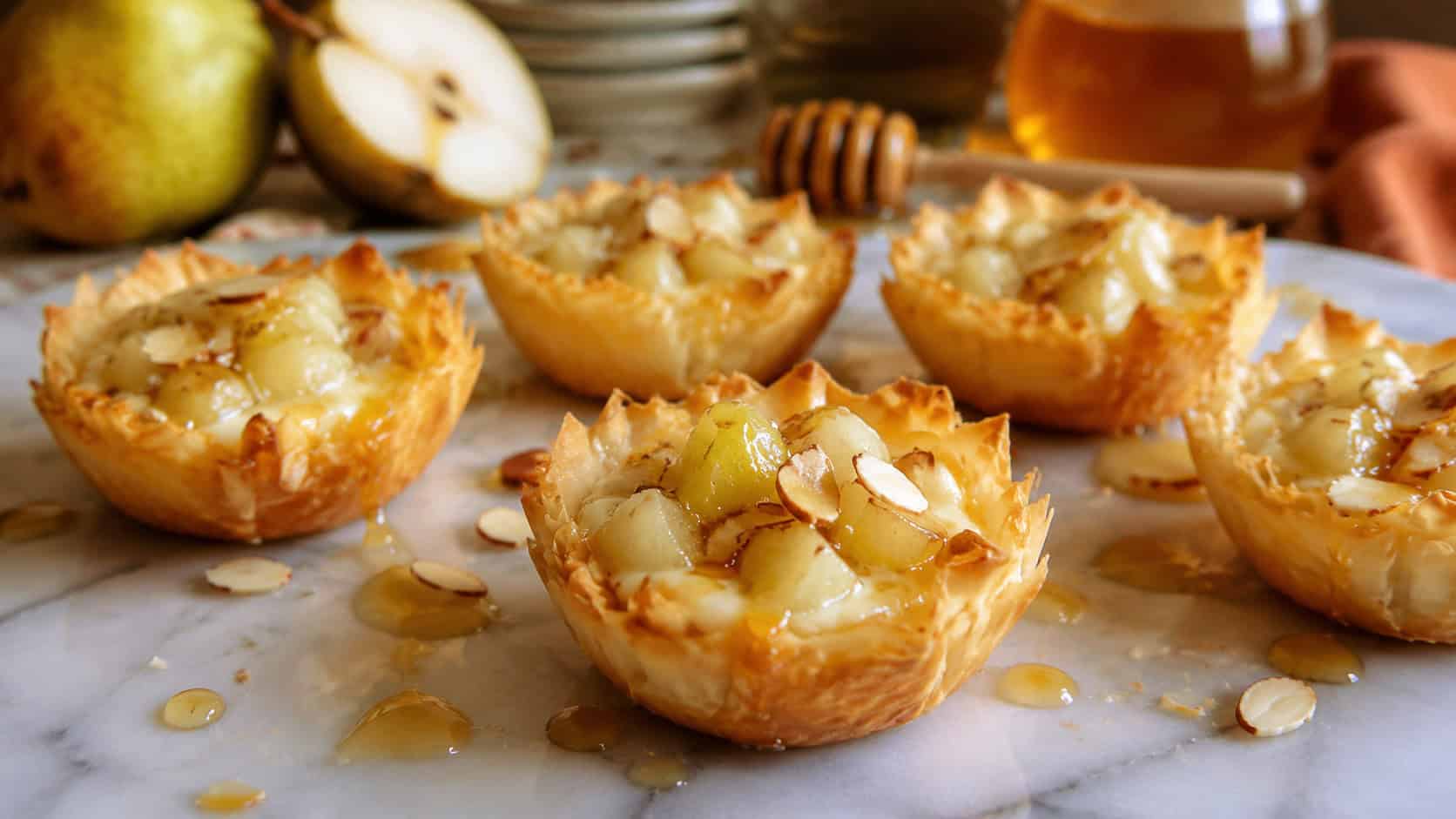 pear and brie phyllo cups on a marble surface, golden flaky pastry filled with melted brie topped with small cubes of pale green pear, toasted sliced almonds and a honey drizzle, soft warm natural light, shallow depth of field, autumn kitchen counter