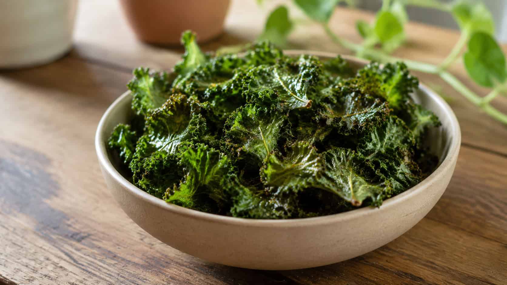 a bowl of crispy baked kale chips with a salty sheen on a wooden table, in a wide horizontal shot, natural light, shallow depth of field, landscape orientation