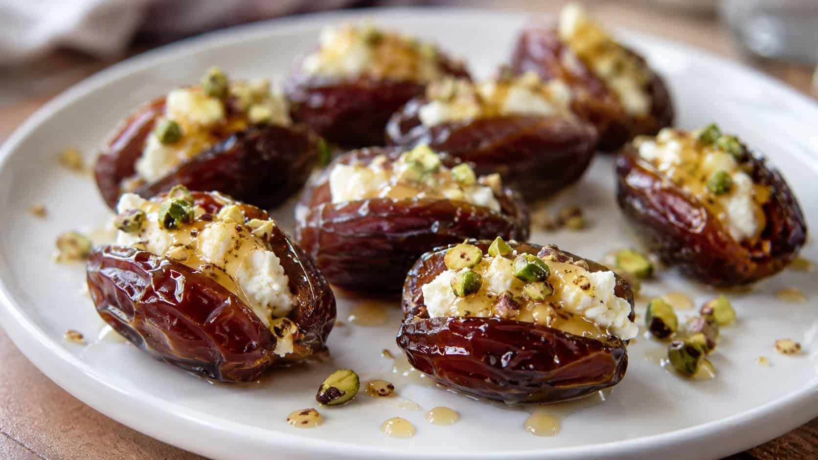 feta-stuffed Medjool dates drizzled with honey and topped with chopped pistachios on a white plate, in a wide horizontal shot, natural light, shallow depth of field, landscape orientation