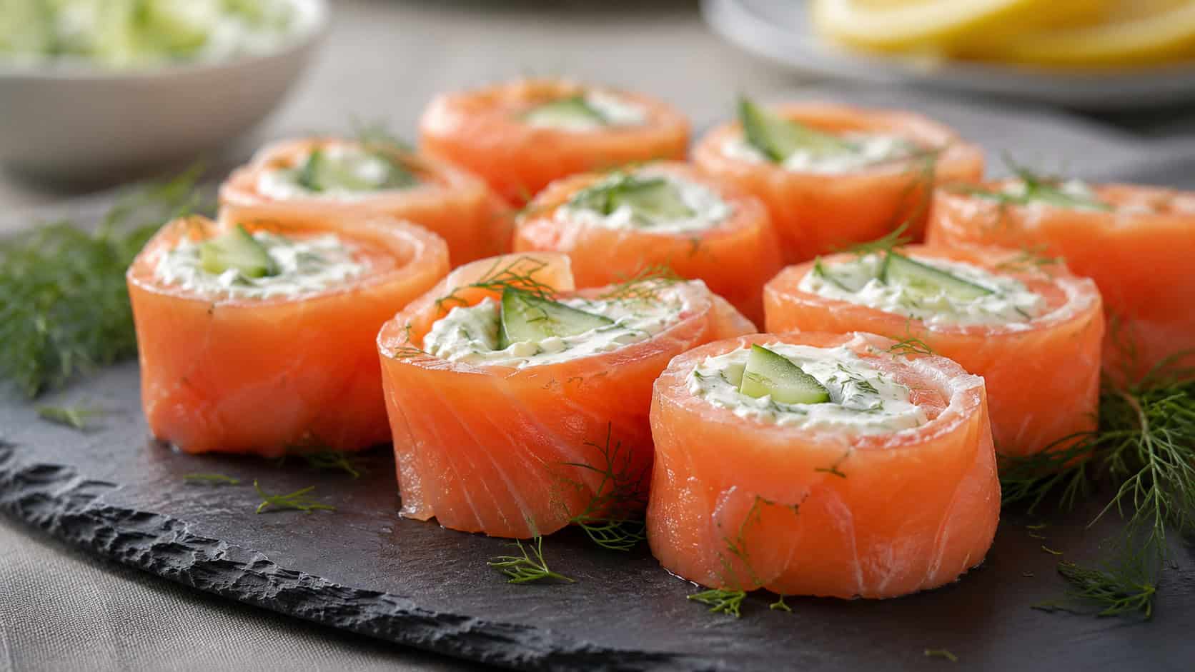 smoked salmon rolls in a wide horizontal shot, pink salmon pinwheels with creamy herb filling and cucumber, arranged on a slate board with dill, soft natural light, shallow depth of field, landscape orientation