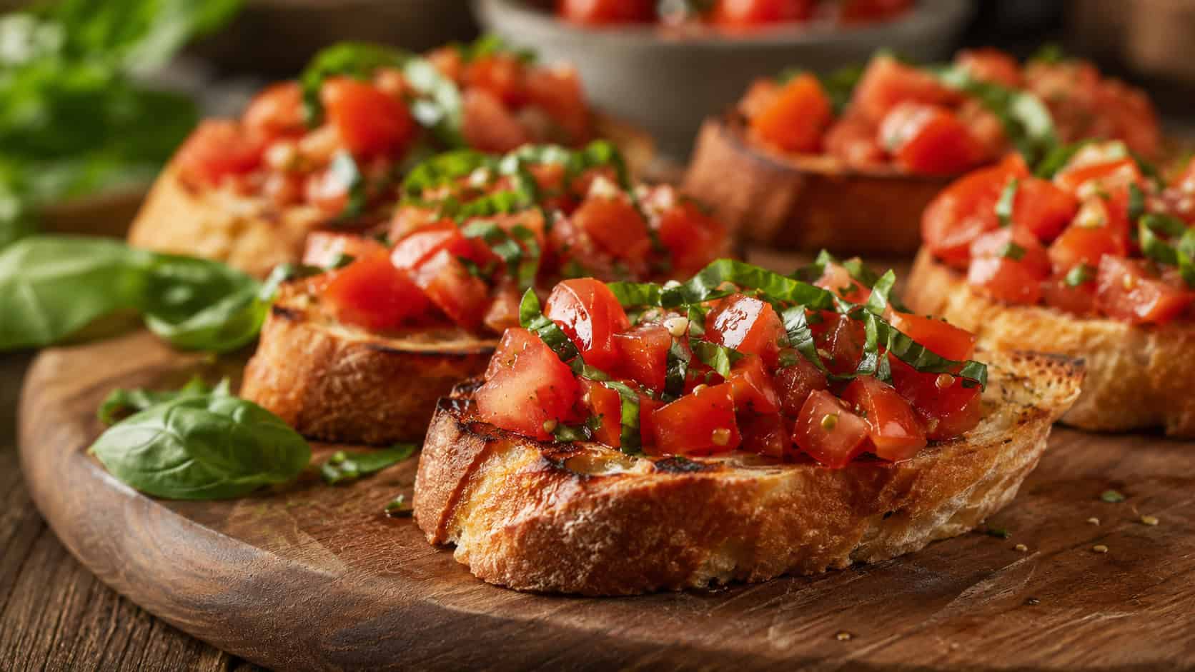 tomato basil bruschetta in a wide horizontal shot, toasted bread slices piled with diced red tomatoes and green basil, arranged on a rustic wooden board, warm natural light, shallow depth of field, landscape orientation