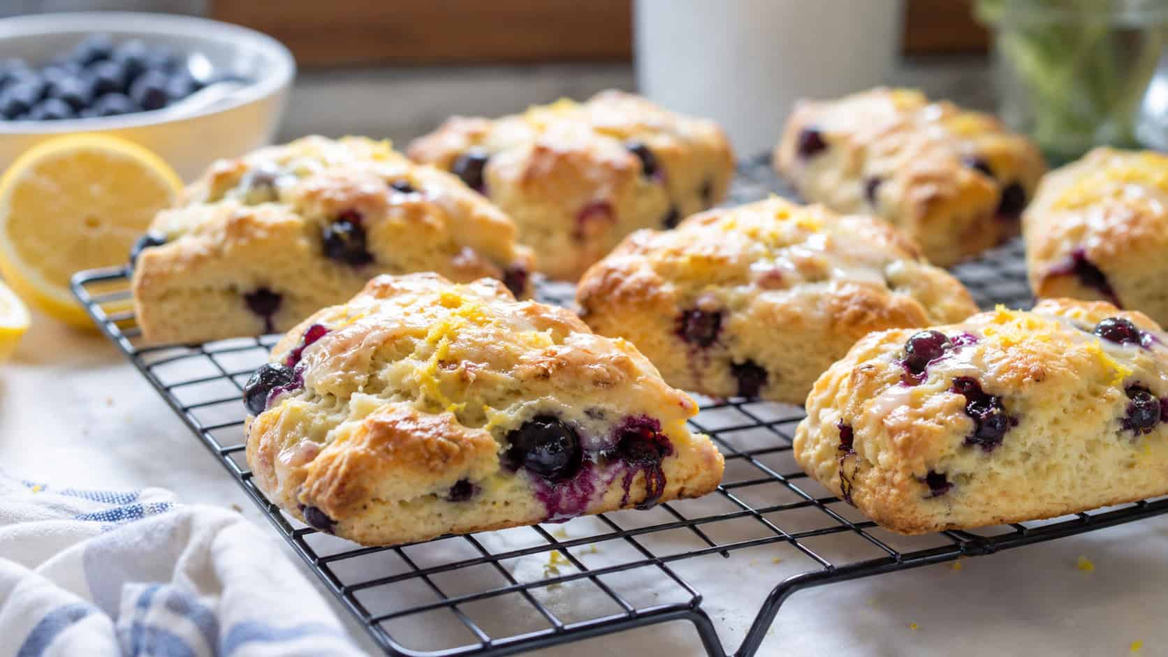 blueberry lemon scones on a wire rack in a wide horizontal shot, golden tops, bursting blueberries, lemon zest, bright morning light, shallow depth of field, landscape orientation