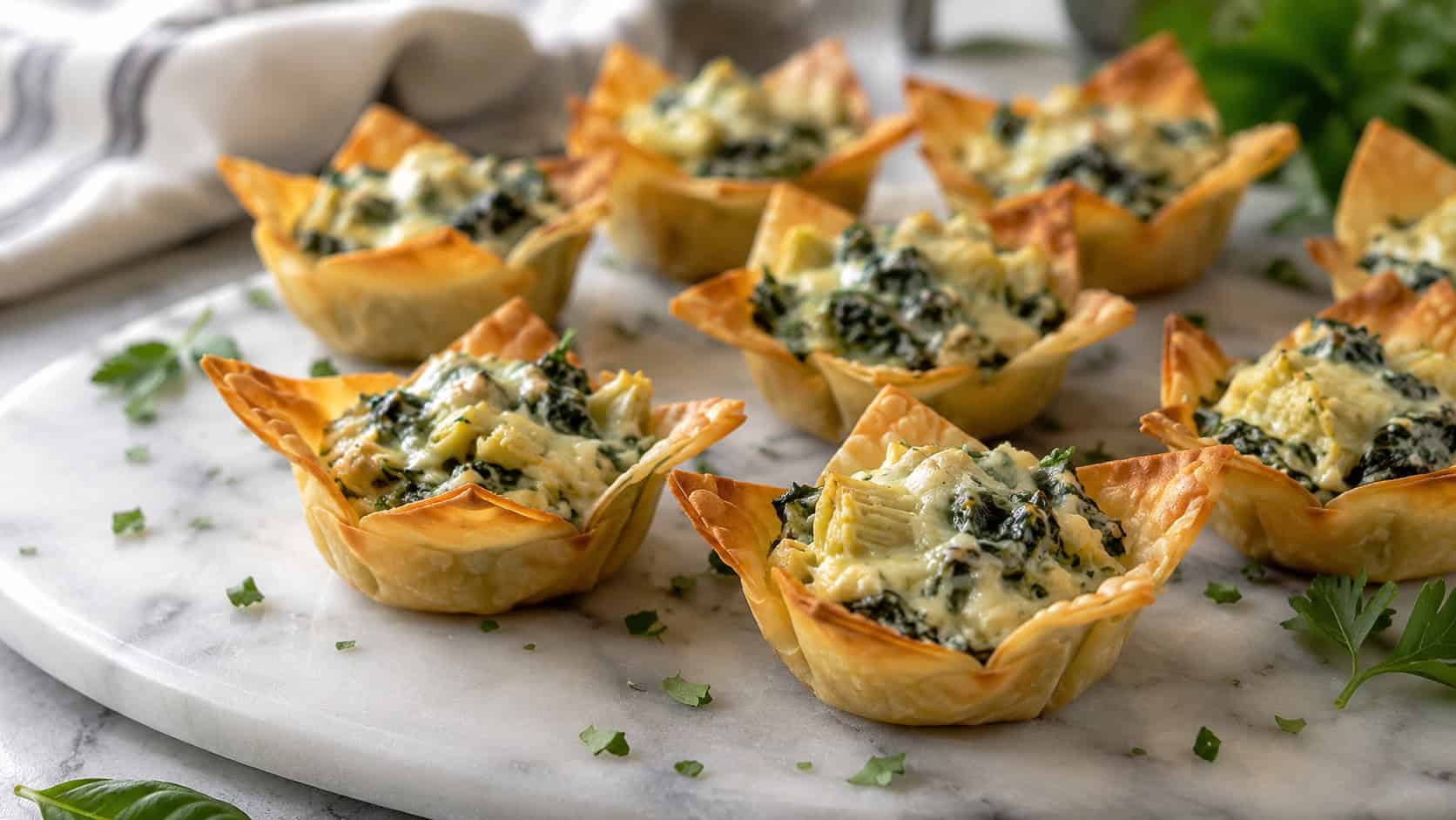 spinach artichoke wonton cups in a wide horizontal shot, creamy green filling in crisp golden shells on a marble board, fresh herbs scattered, natural light, shallow depth of field, landscape orientation