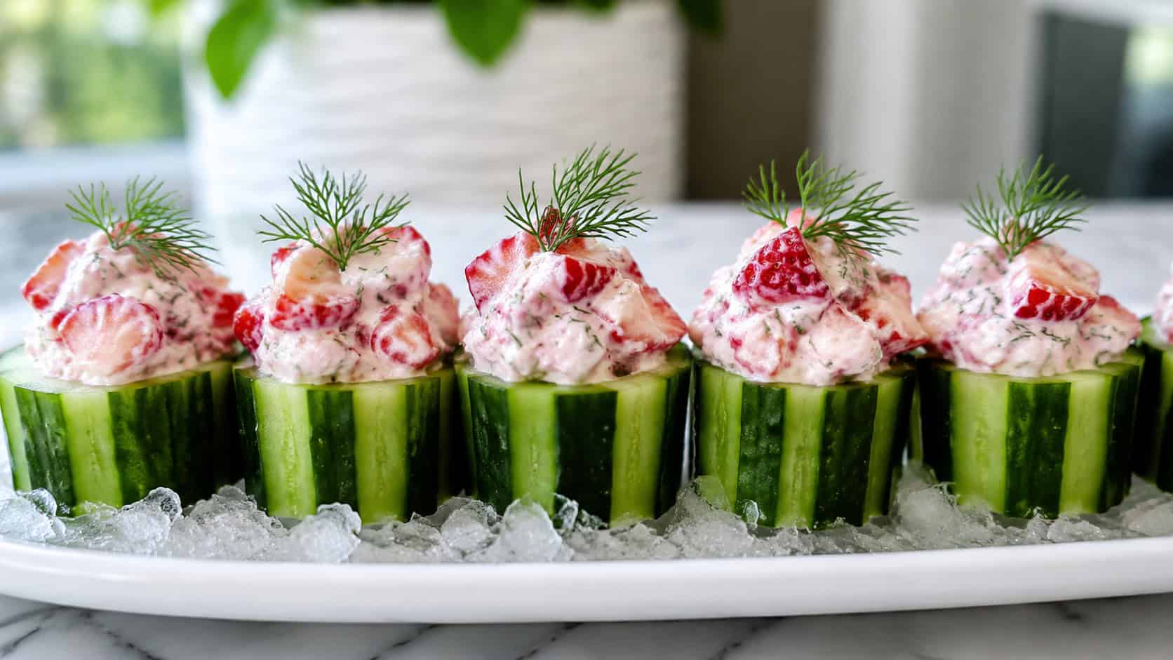 cucumber cups filled with creamy strawberry salad and fresh dill, arranged in a wide horizontal row on a chilled white platter, crisp and fresh, bright natural light, shallow depth of field, landscape orientation