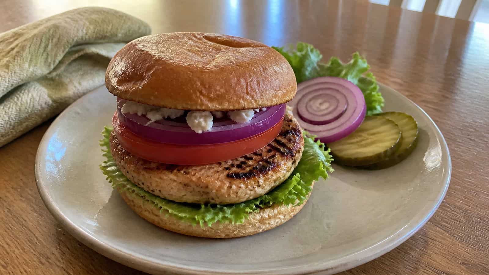 a juicy turkey burger on a simple plate at a home kitchen table