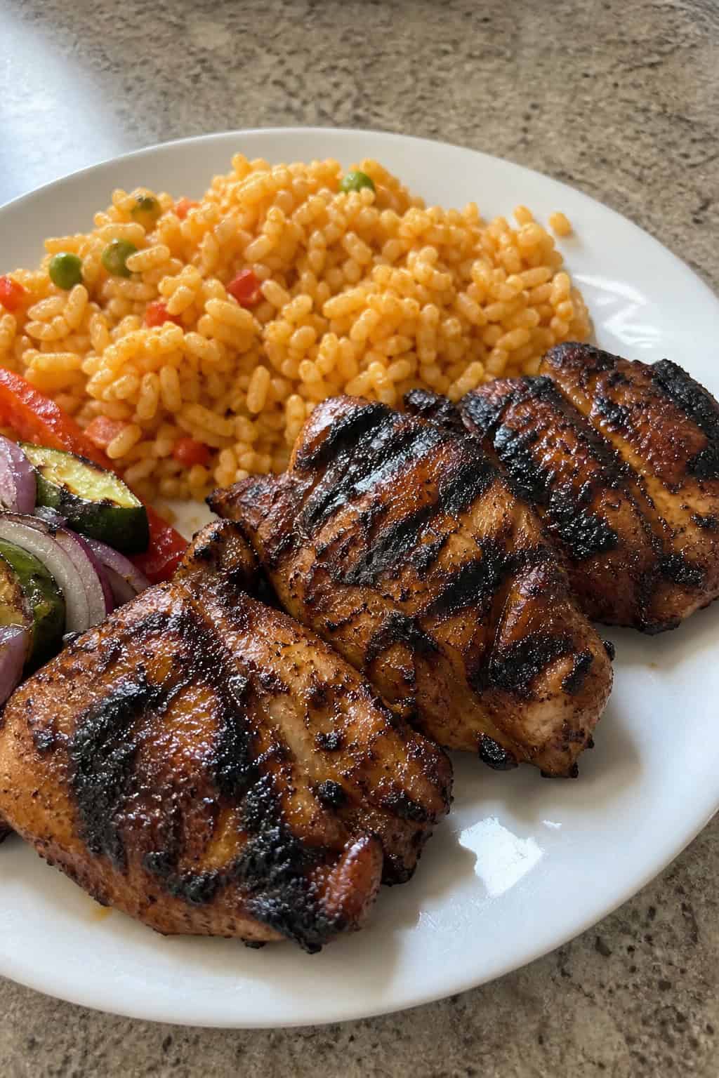 18 Chipotle Copycat Recipes to Make at Home 16 A plate of grilled adobo-marinated chicken served with rice, grilled vegetables, lime wedges, and fresh herbs.