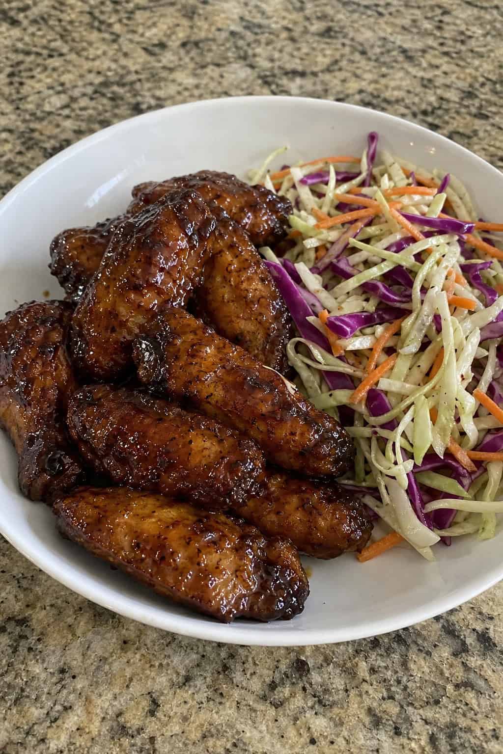22 Chicken Wing Recipes for Game Day and Beyond 9 A plate of Asian five-spice hoisin chicken wings served with colorful cabbage slaw on a wooden table.