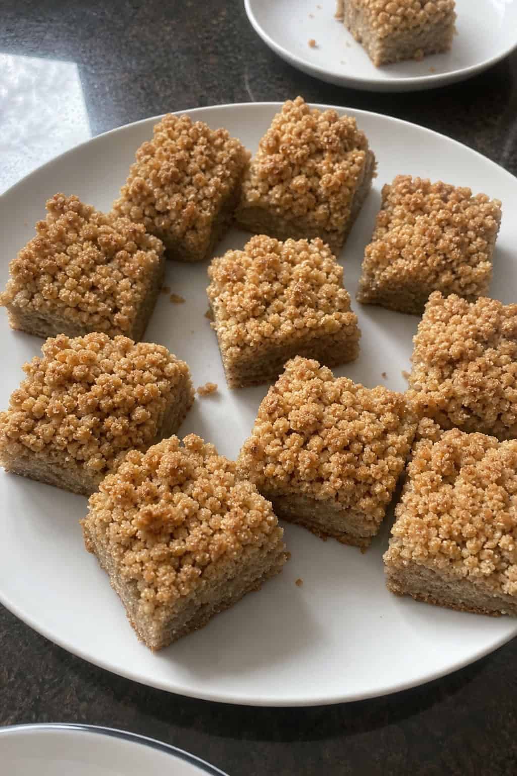 Freshly baked banana bread cookie bars with streusel topping arranged on a wooden board with ripe bananas nearby.